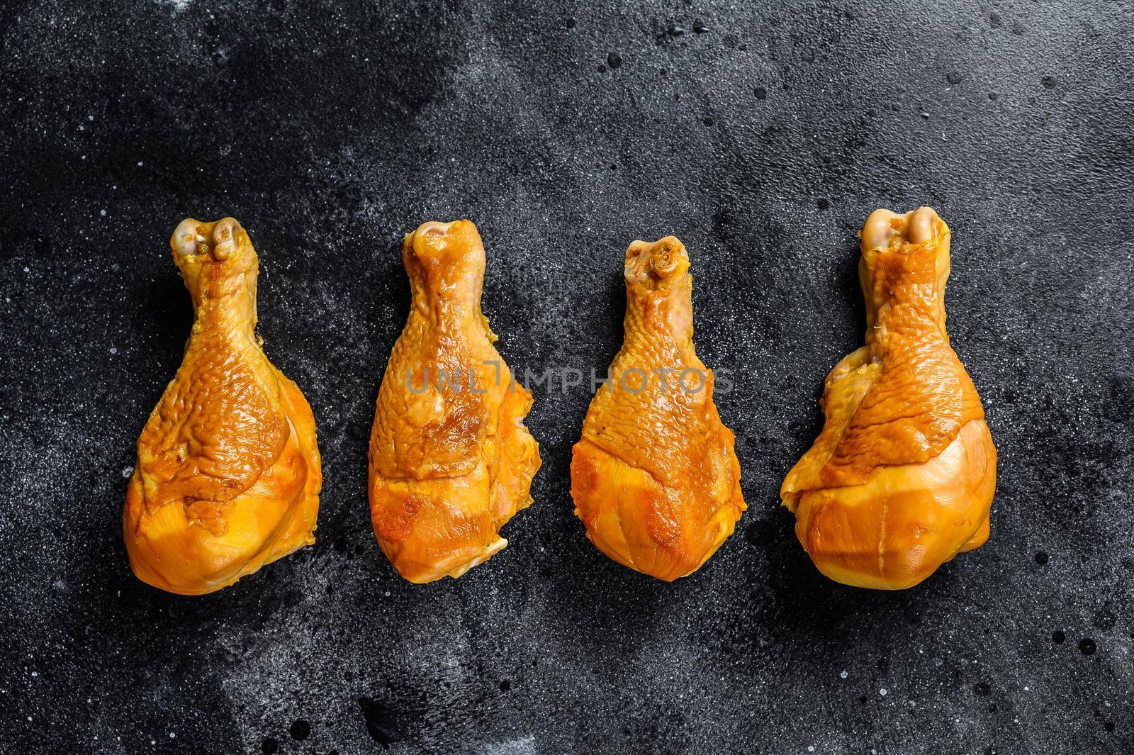 Spicy Smoked chicken leg drumsticks on a kitchen table. Black background. Top view by Composter