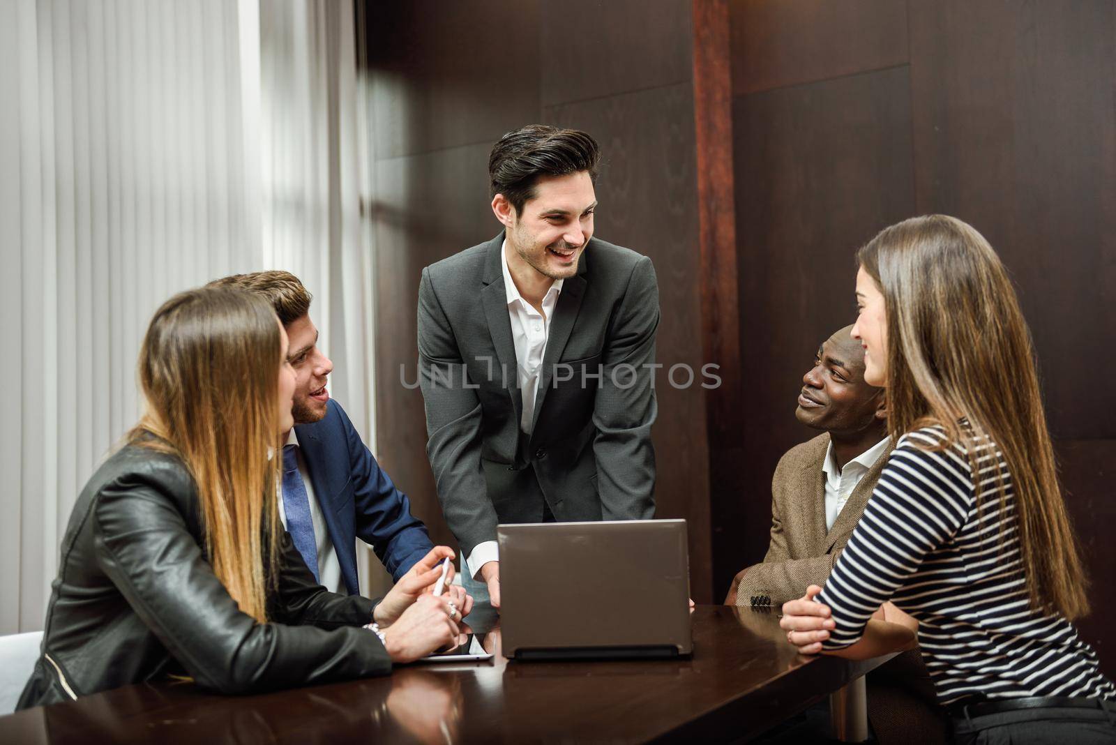 Businesspeople, teamwork. Group of multiethnic busy people working in an office. Male as leader wearing blazer jacket.