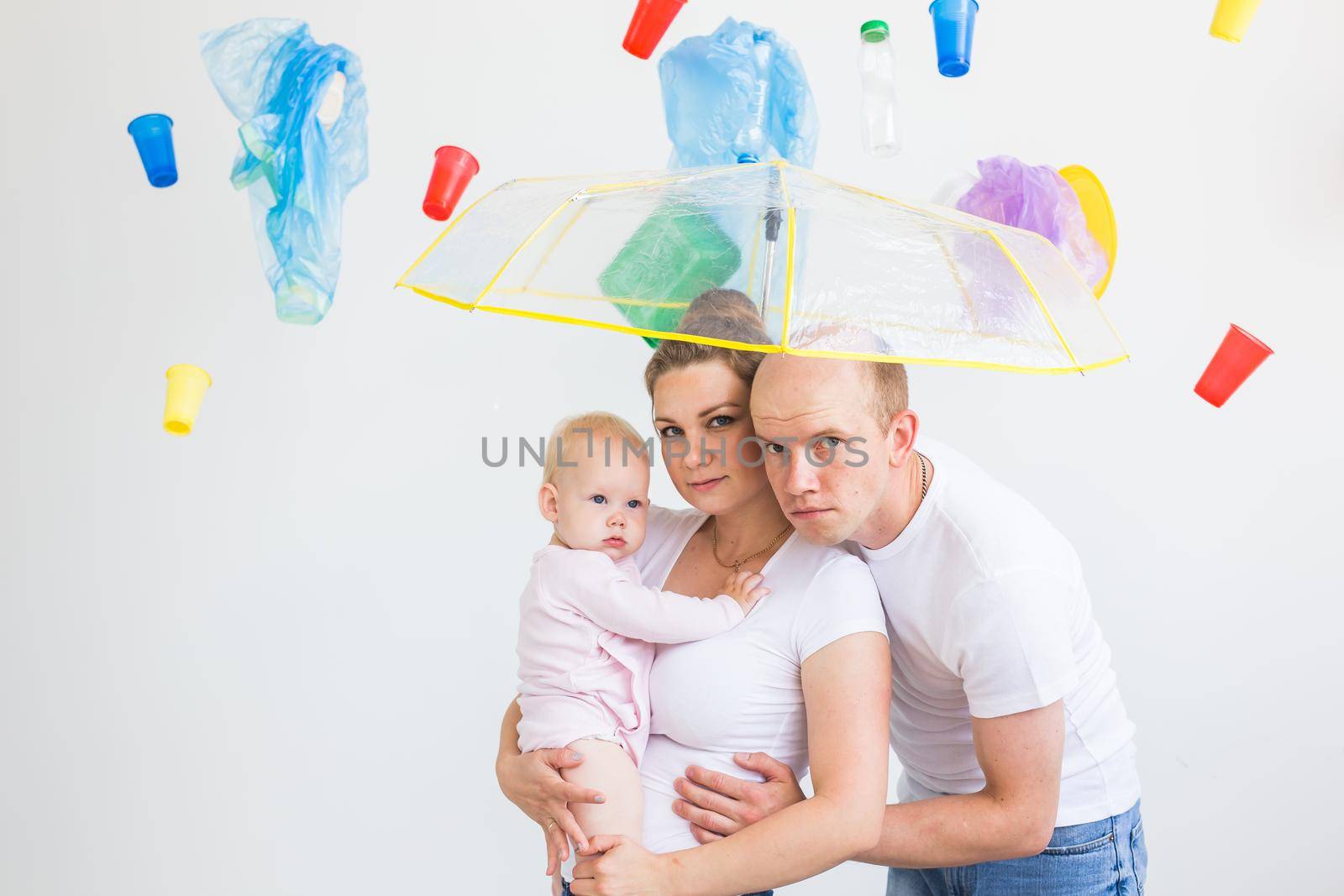 World Environment Day, plastic recycling problem and environmental disaster concept - Sad family hiding from garbage under an umbrella on white background.