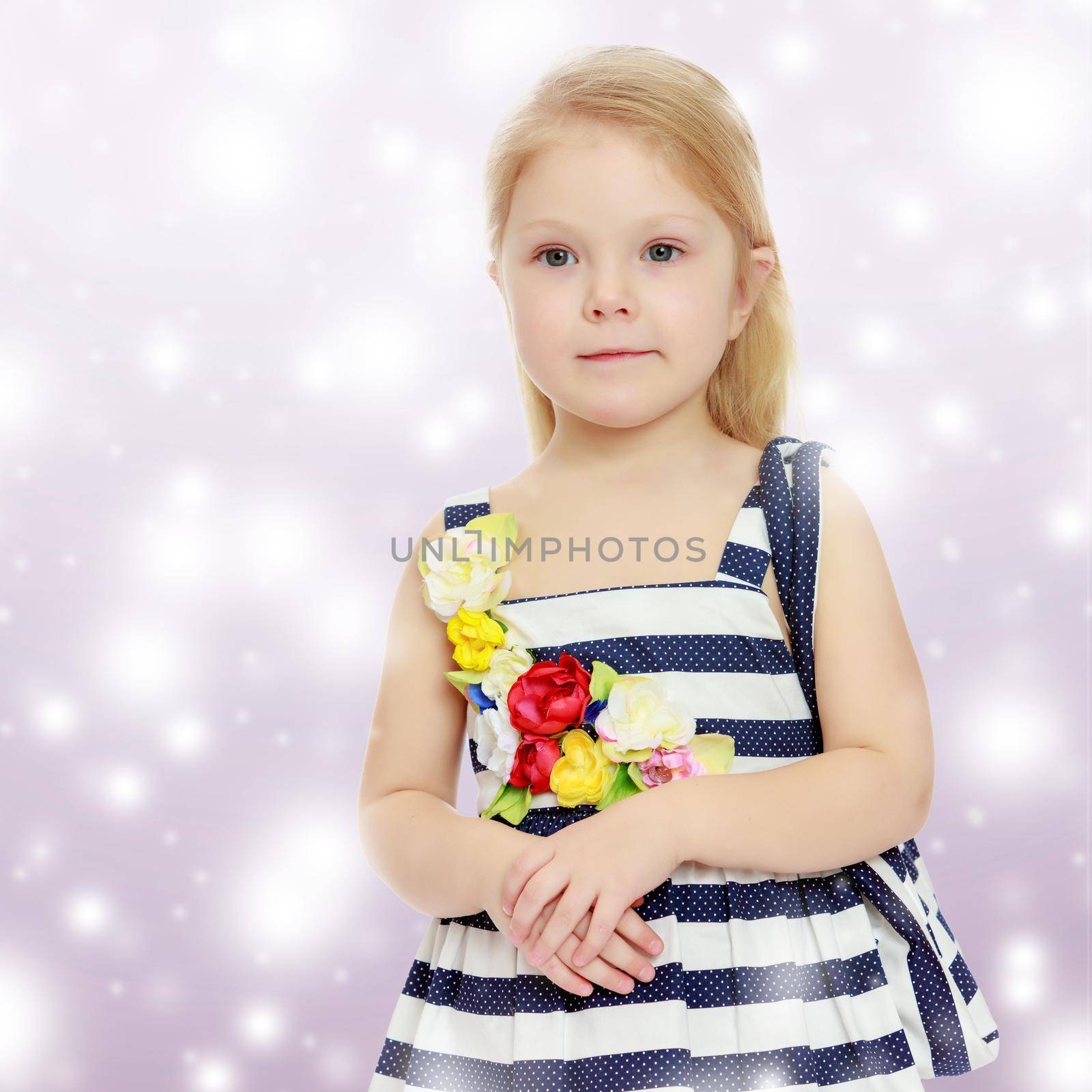 The little blonde girl in striped summer dress with beach bag on shoulder.