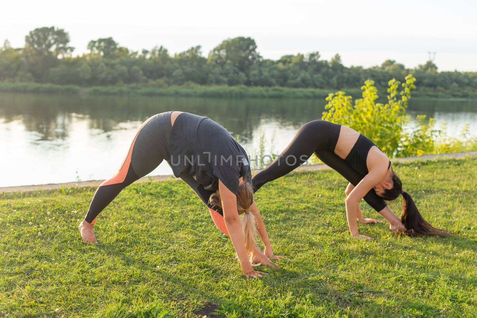 Healthy lifestyle and people concept - Flexible women doing yoga in the summer park.