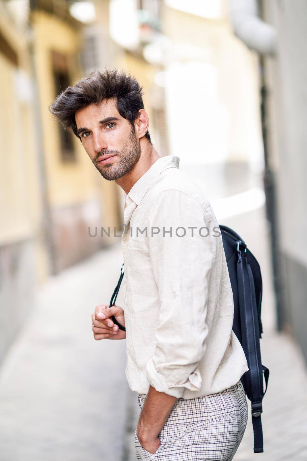 Young man sightseeing enjoying the streets of Granada, Spain. Male traveler carrying backpack in urban background.