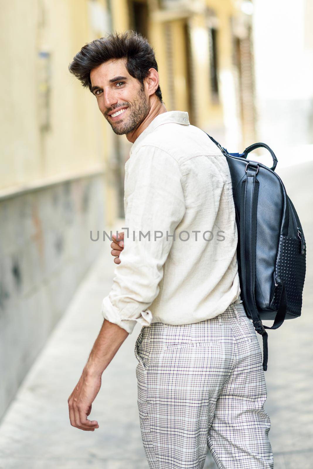 Young man sightseeing enjoying the streets of Granada, Spain. Male traveler carrying backpack in urban background.