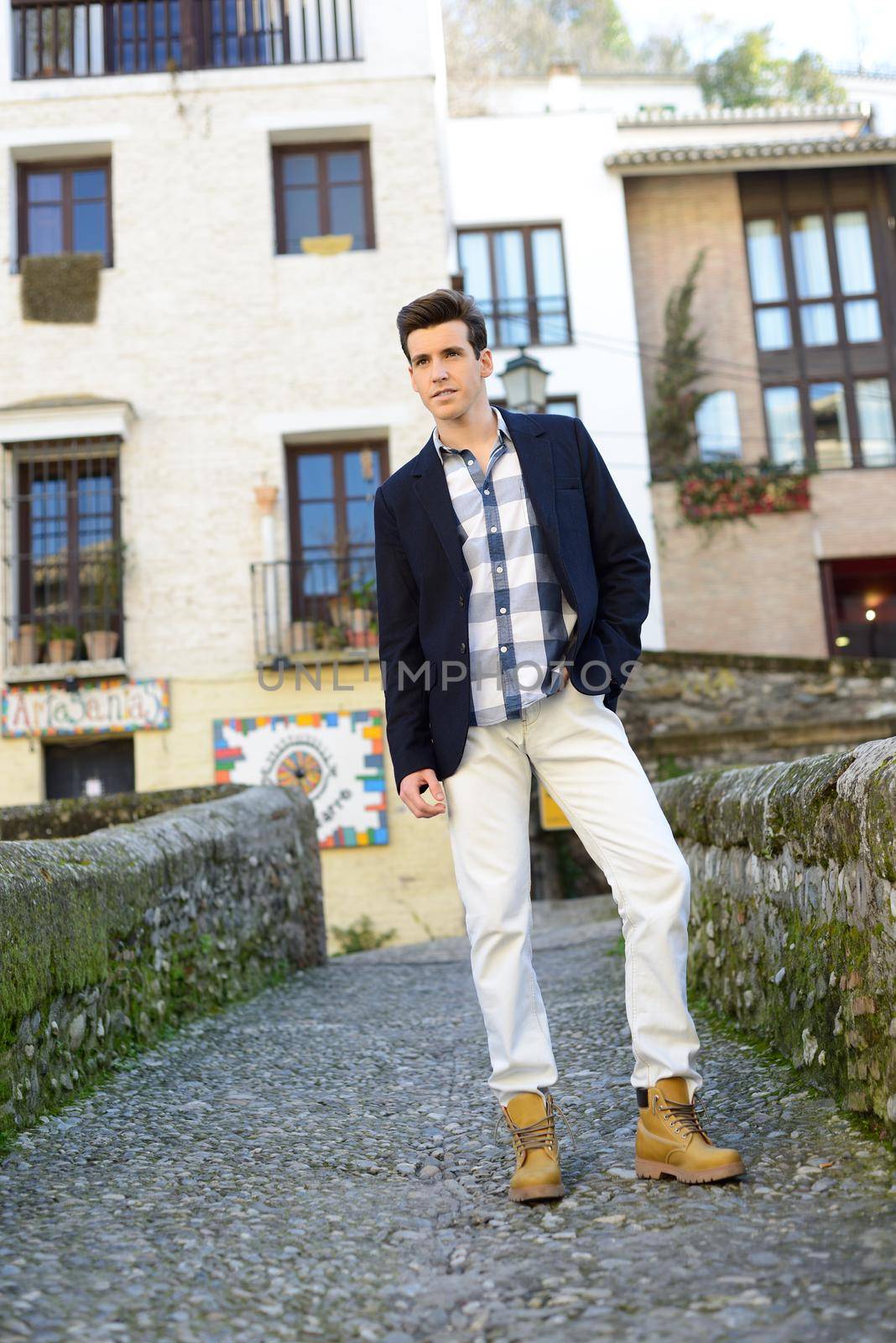 Portrait of handsome man with modern hairstyle smiling in urban background