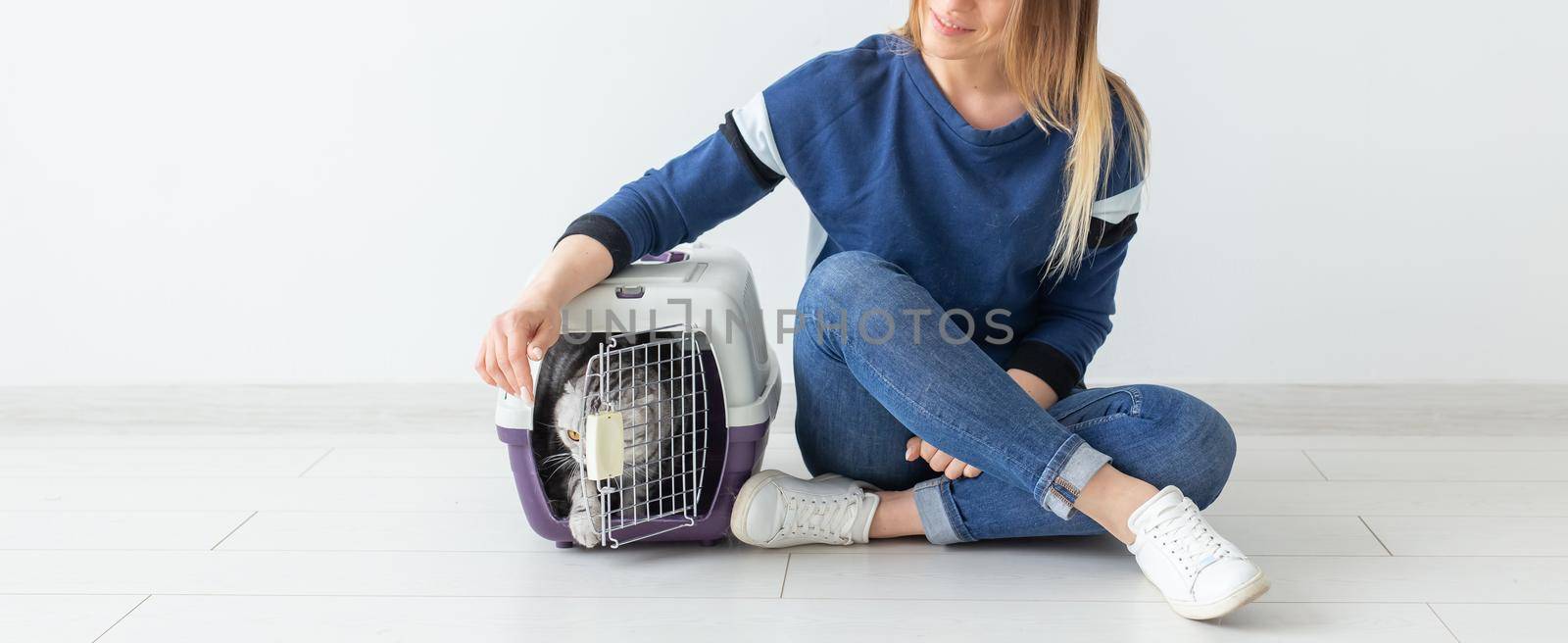 Positive good-looking woman and beautiful gray Scottish Fold cat into her new apartment after the move. Housewarming and pets concept. by Satura86