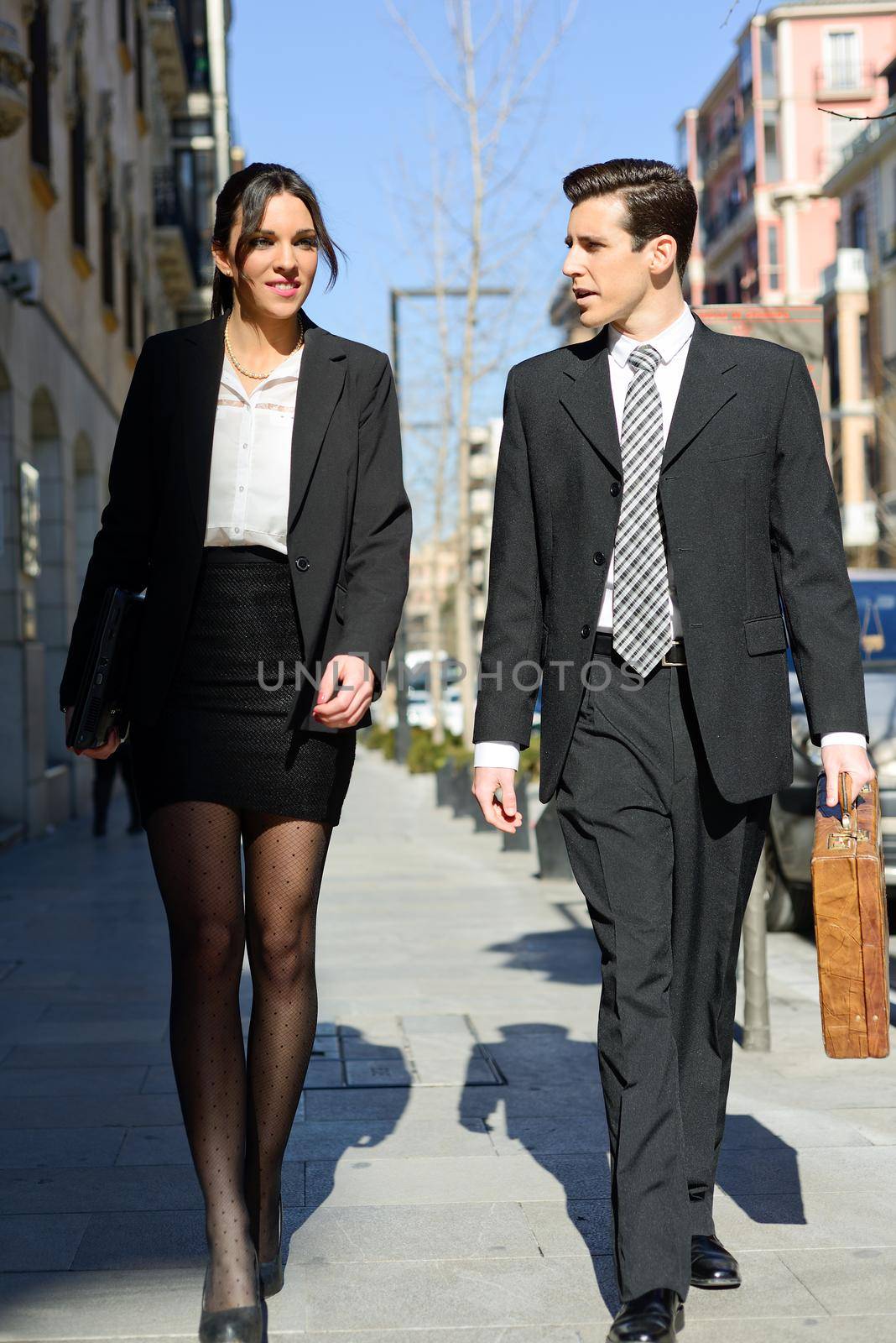 Portrait of an atractive business people walking on the street. Couple working.