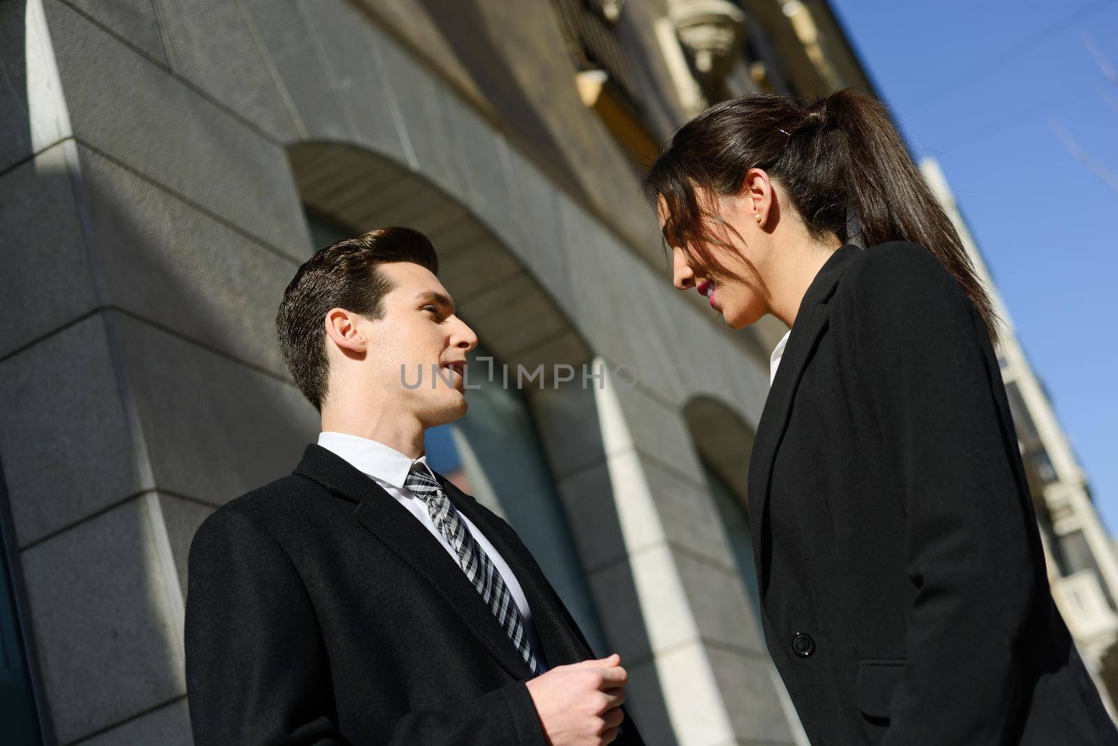 Business people talking outside of company building. Couple working by javiindy