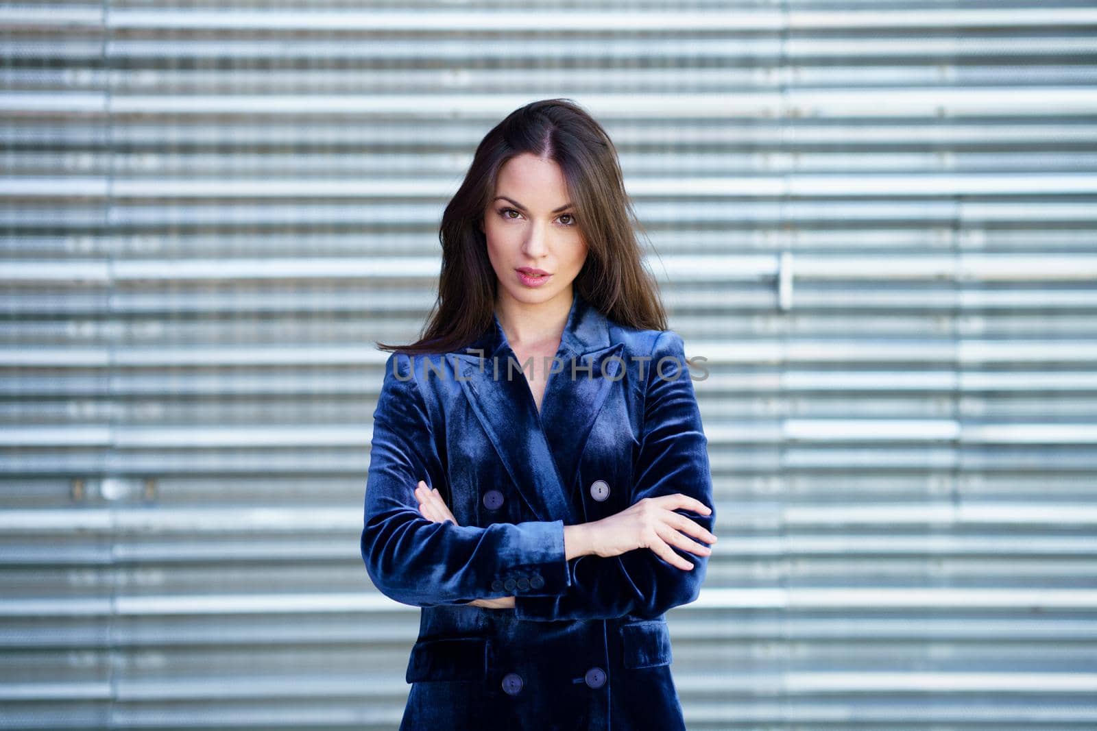 Woman wearing blue suit posing near a modern metal building. Lifestyle concept.