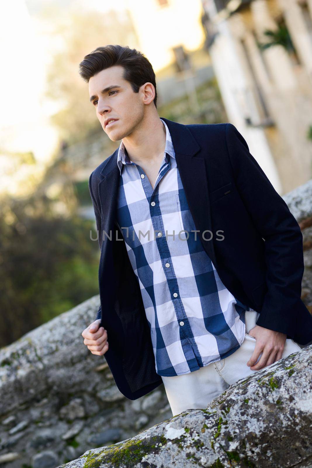 Portrait of handsome man with modern hairstyle smiling in urban background