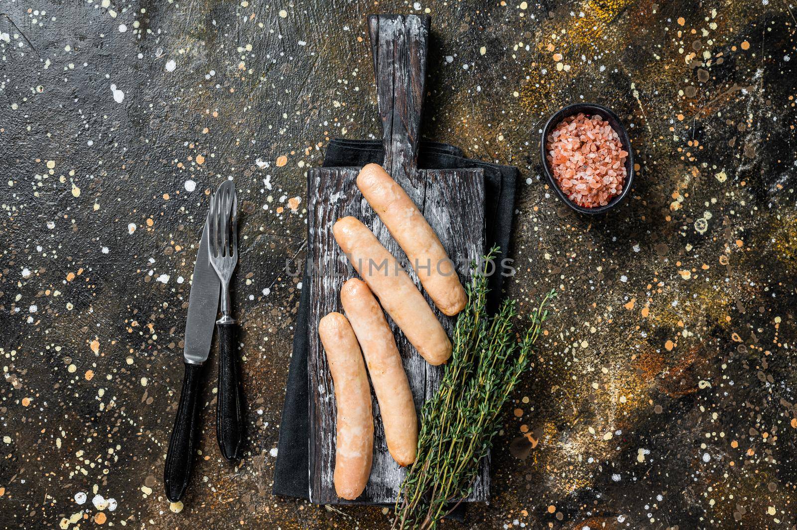 Grilled chicken sausages on a wooden board. Brown background. Top view by Composter