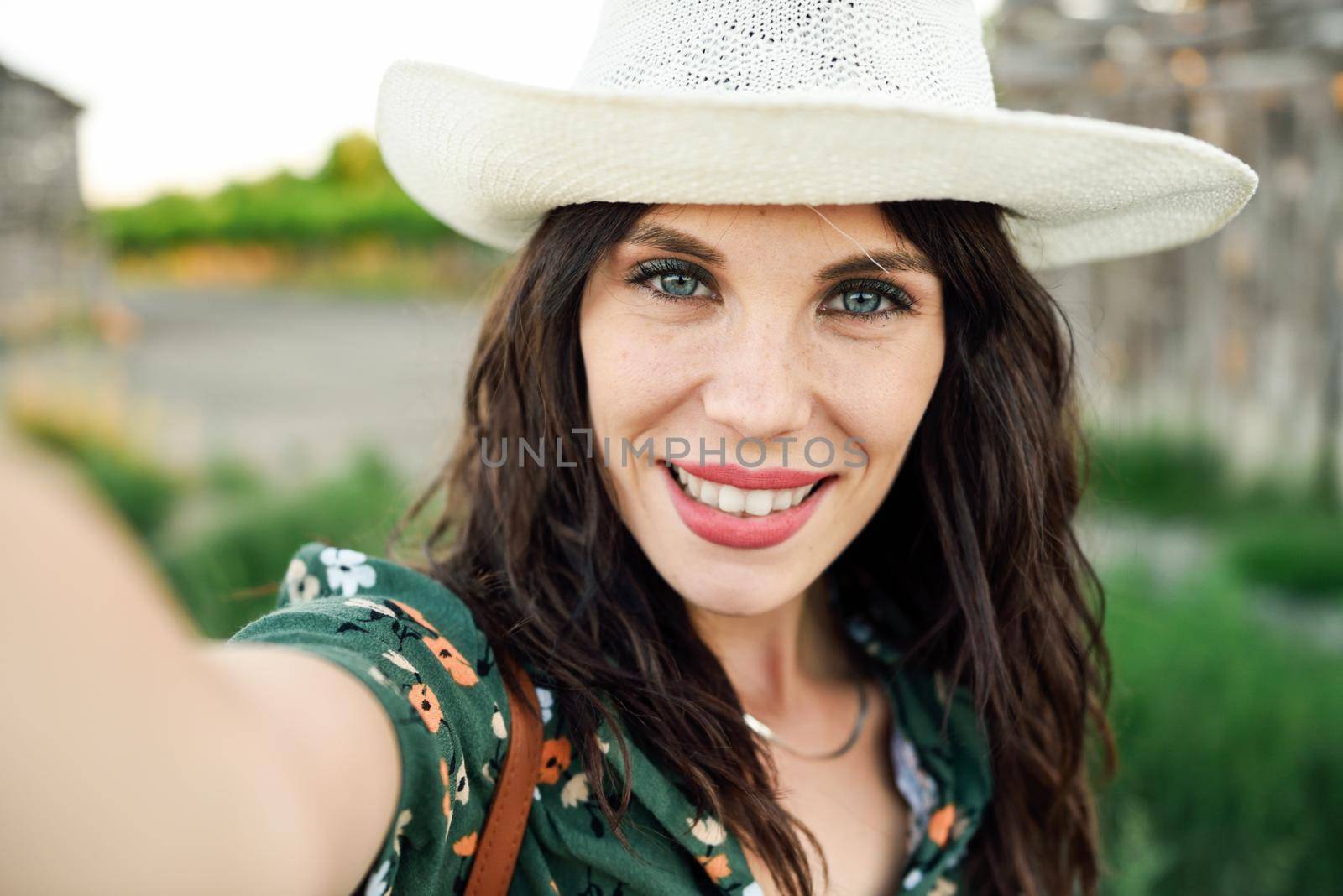 Beautiful hiker young woman, wearing flowered shirt, taking a selfie photograph outdoors