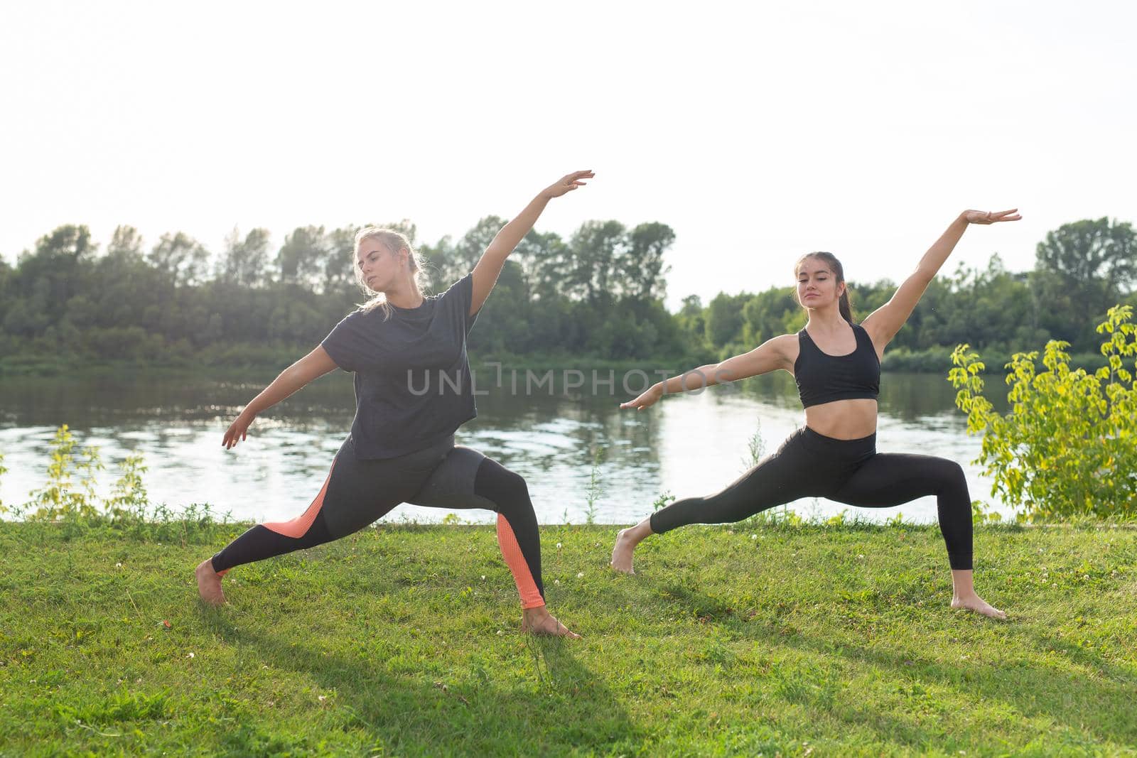 Healthy lifestyle and people concept - Flexible women doing yoga in the summer park.