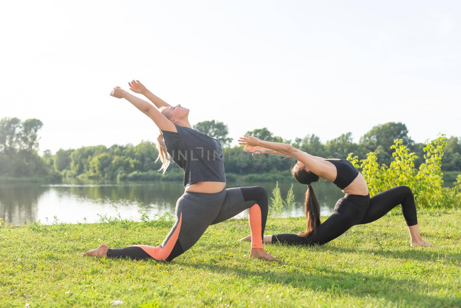 Healthy lifestyle and people concept - Flexible women doing yoga in the summer park.