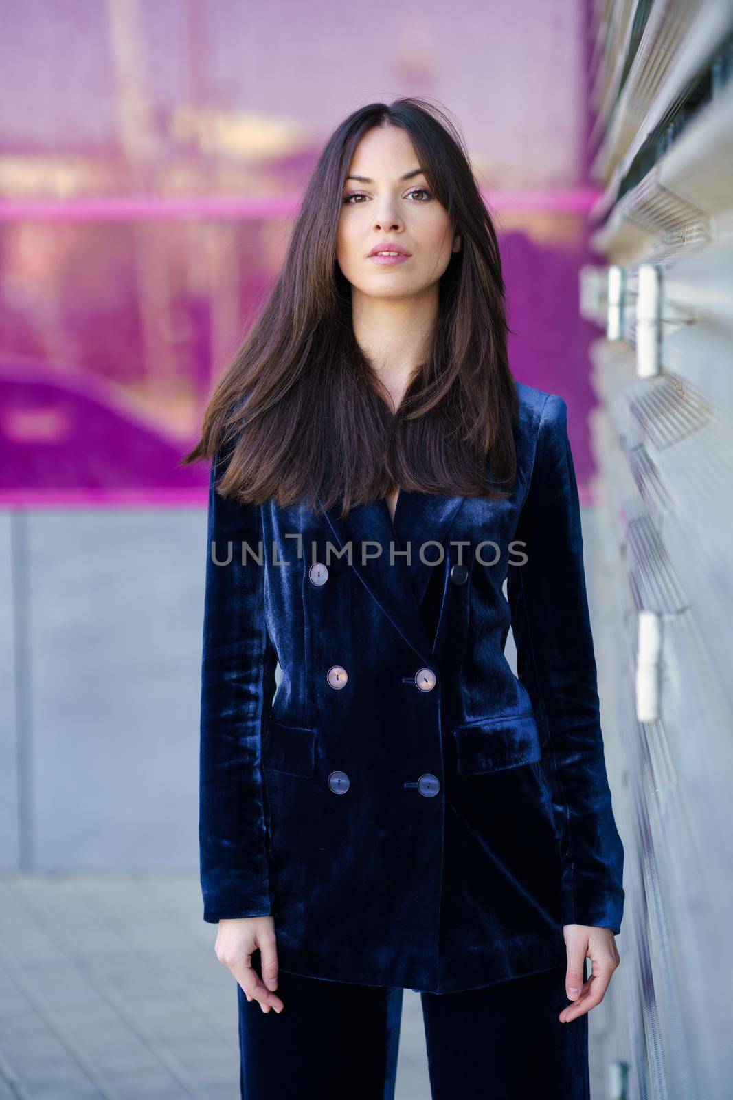 Woman wearing blue suit posing near a modern building. Lifestyle concept.