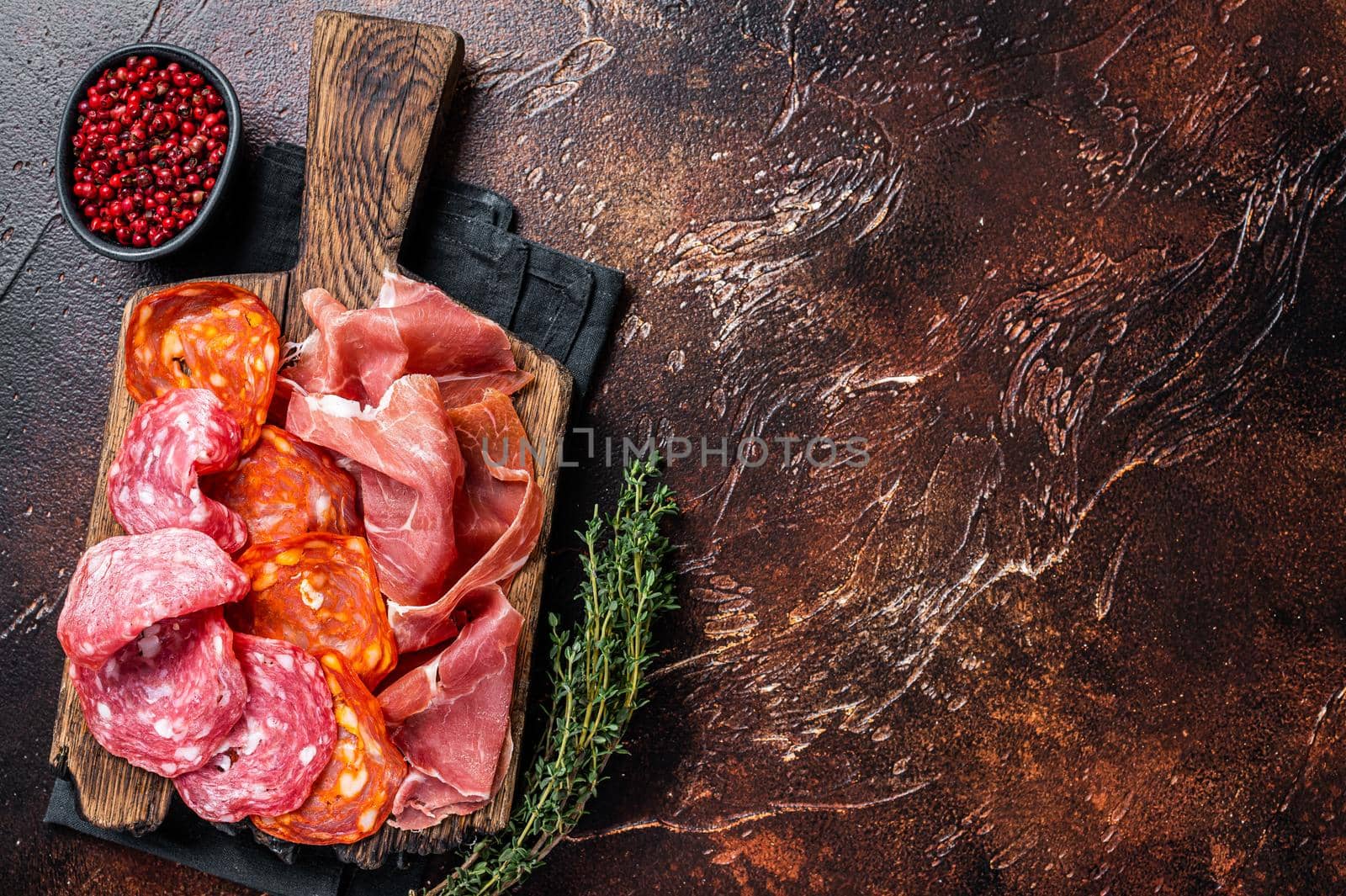 Spanish meat tapas - salami, jamon, choriso cured sausages. Dark background. Top view. Copy space by Composter