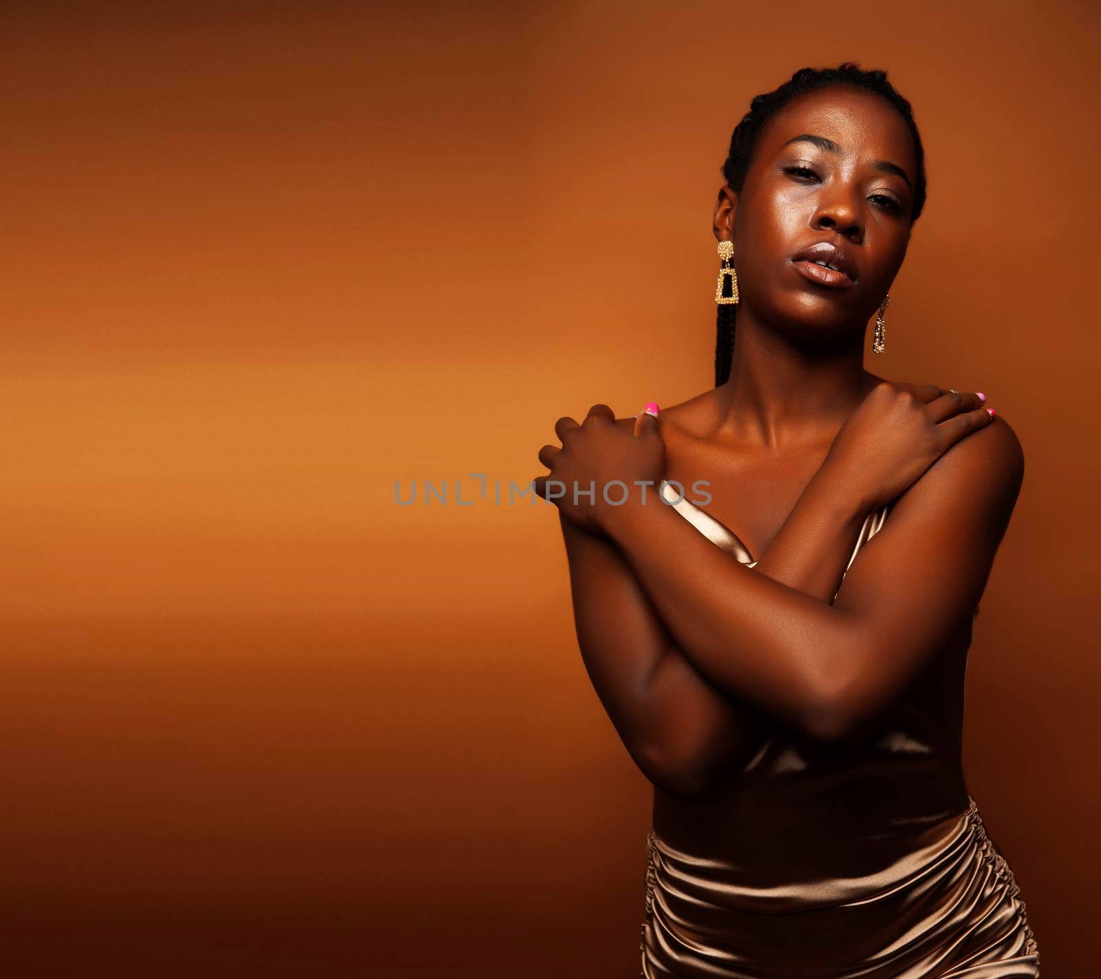 pretty young african american woman with braids posing cheerful gesturing on brown background, lifestyle people concept close up