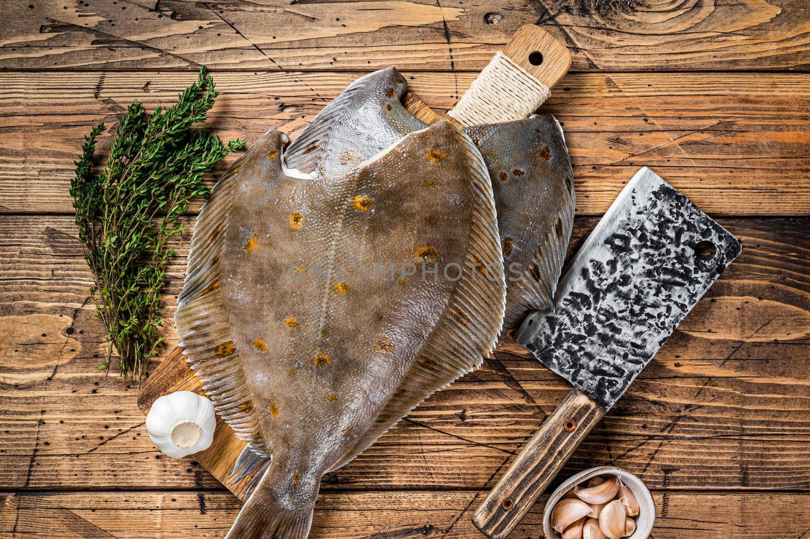 Raw flounder flatfish on butcher board with cleaver. wooden background. Top view by Composter