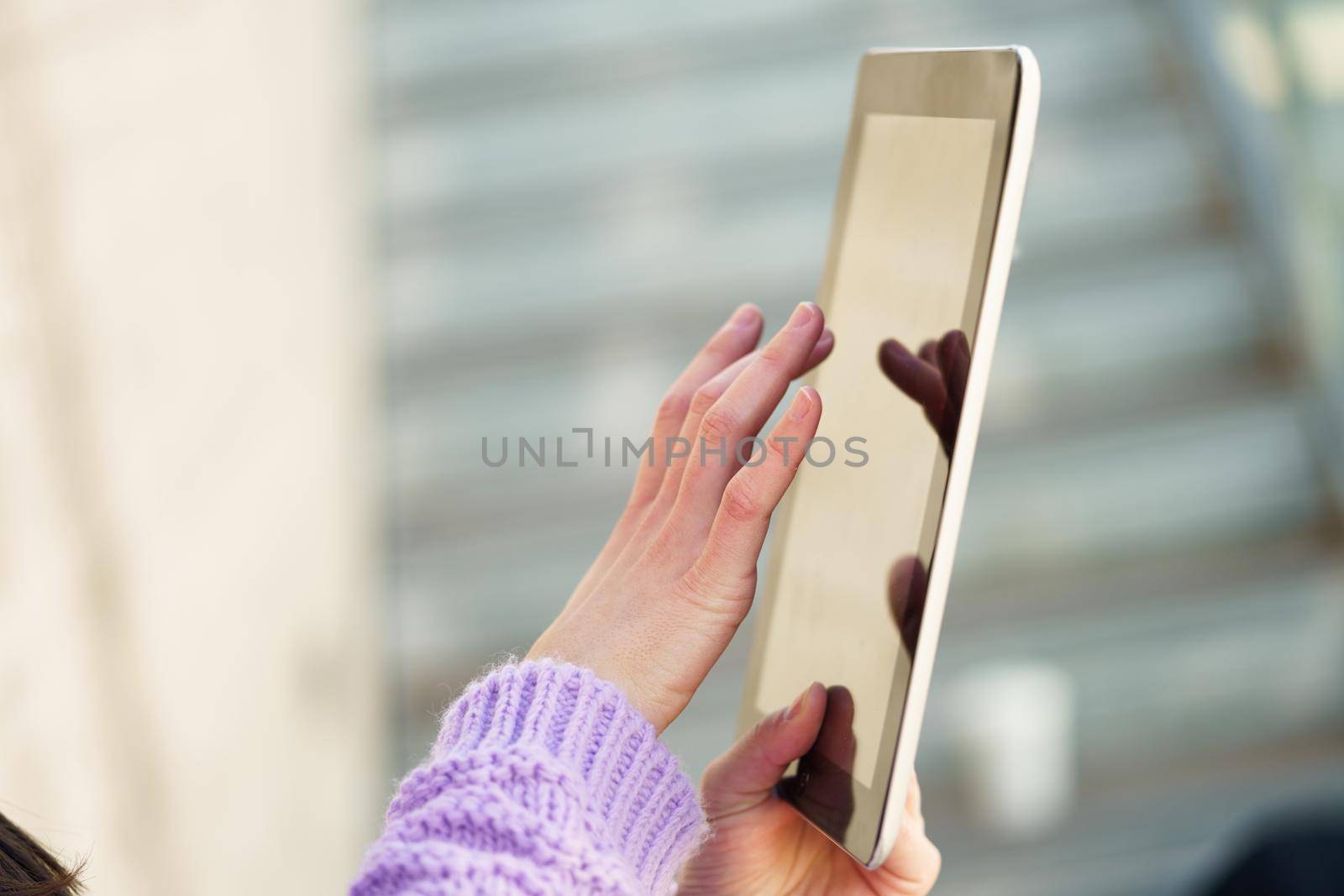 Detail of unrecognizable woman using digital tablet outdoors. Lifestyle concept.