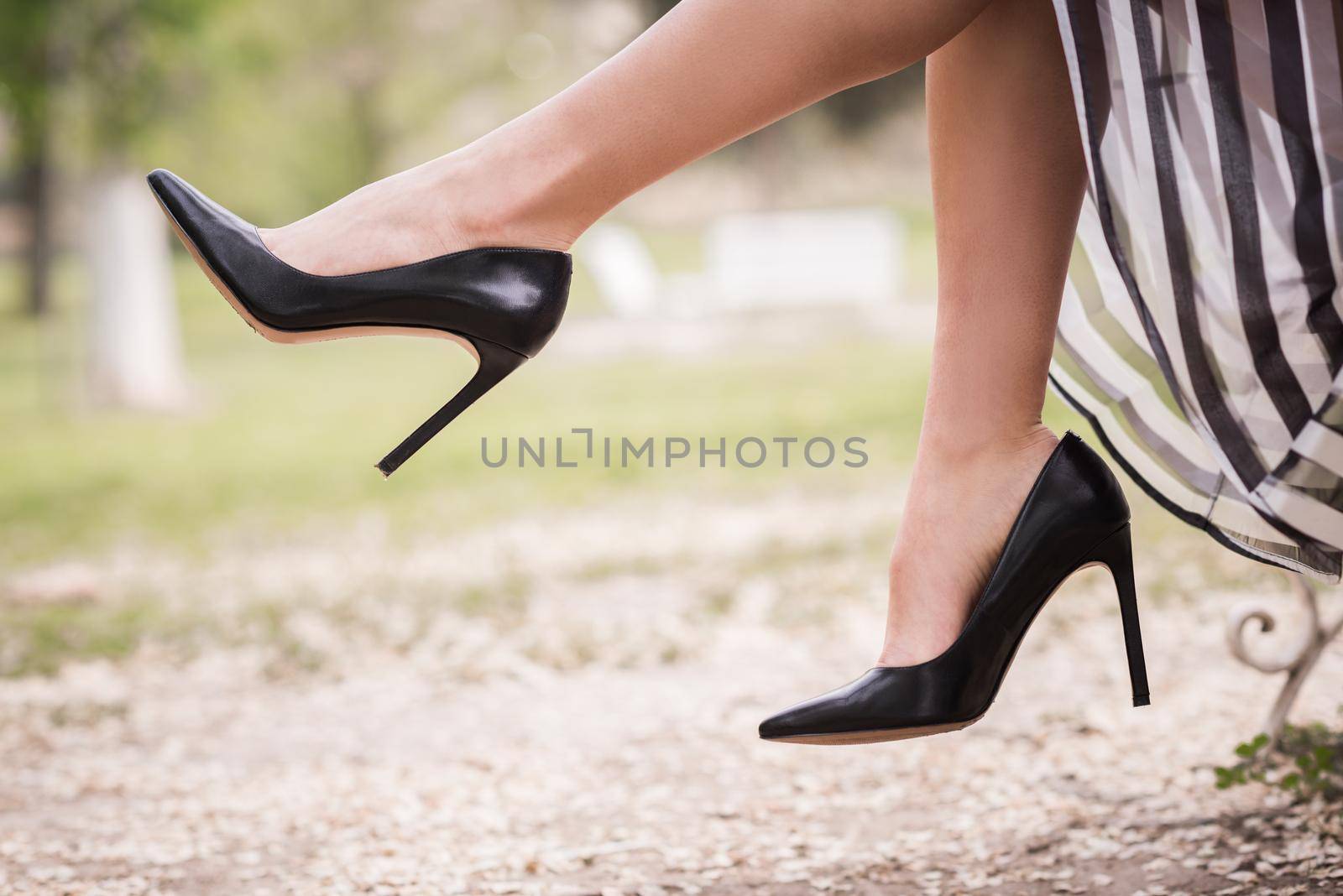 Black high heels on the feet of a young woman by javiindy