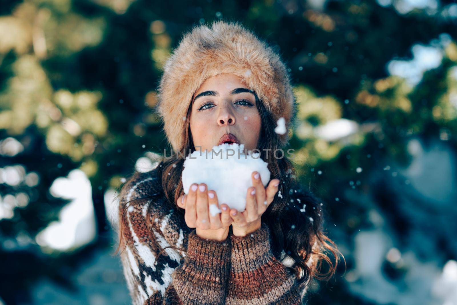 Young woman enjoying the snowy mountains in winter, in Sierra Nevada, Granada, Spain. Female wearing winter clothes playing with snow.