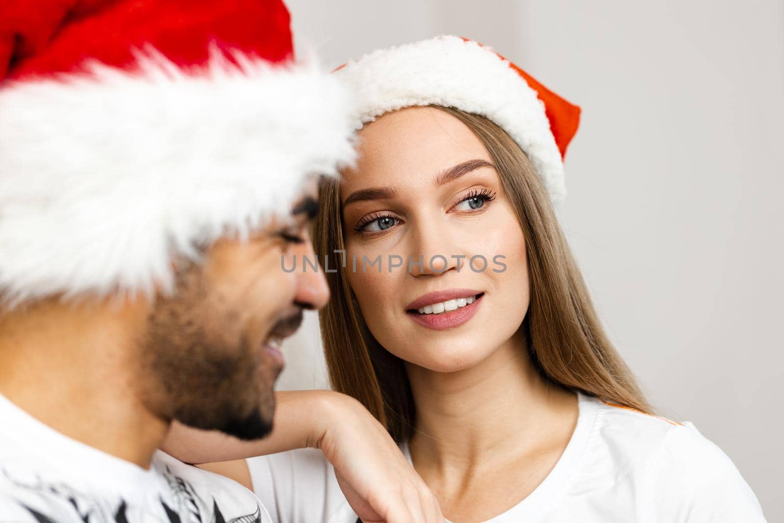 Cheerful attractive happy couple in Santa hats, close up portrait
