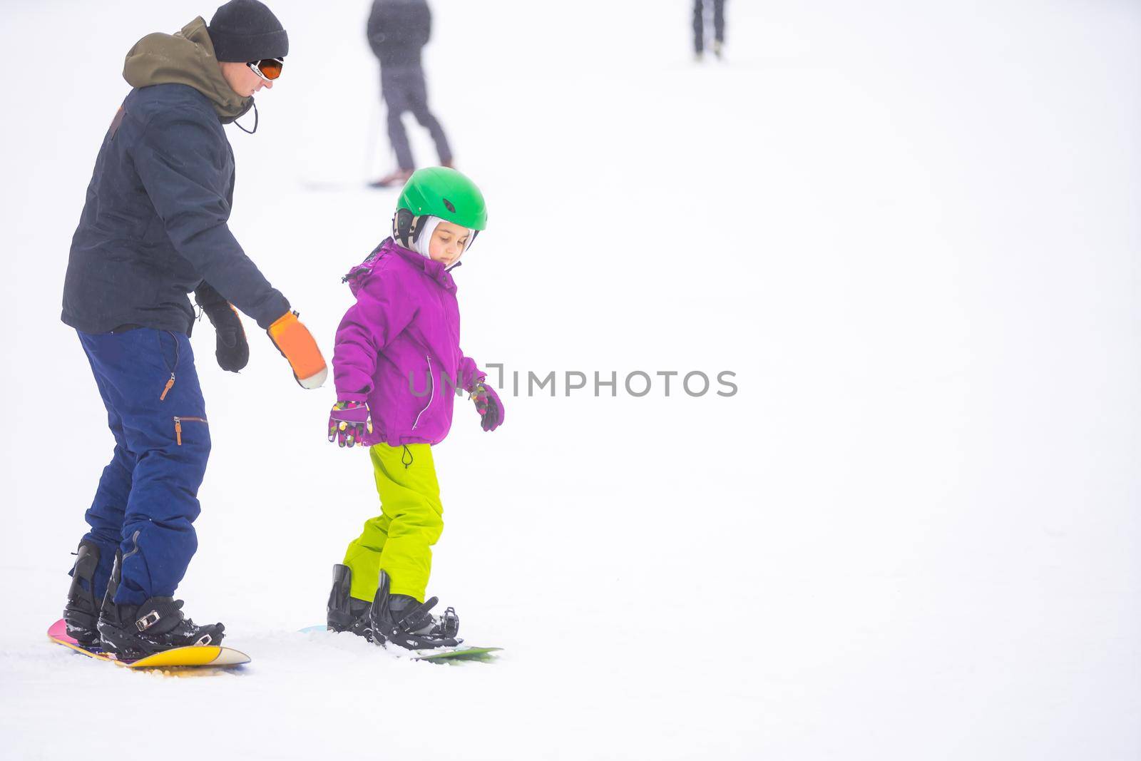 At Cold Winder Day at Mountain Ski Resort Father Teaching Little Daughter Snowboarding