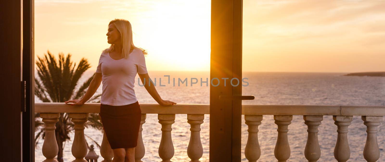 Woman admiring sunset from her balcony by Andelov13