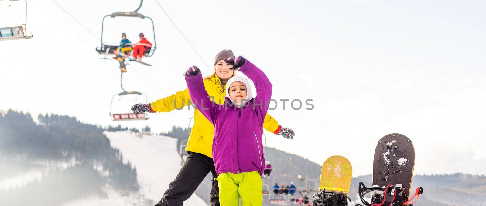 mother and daughter with snowboards at winter resort by Andelov13