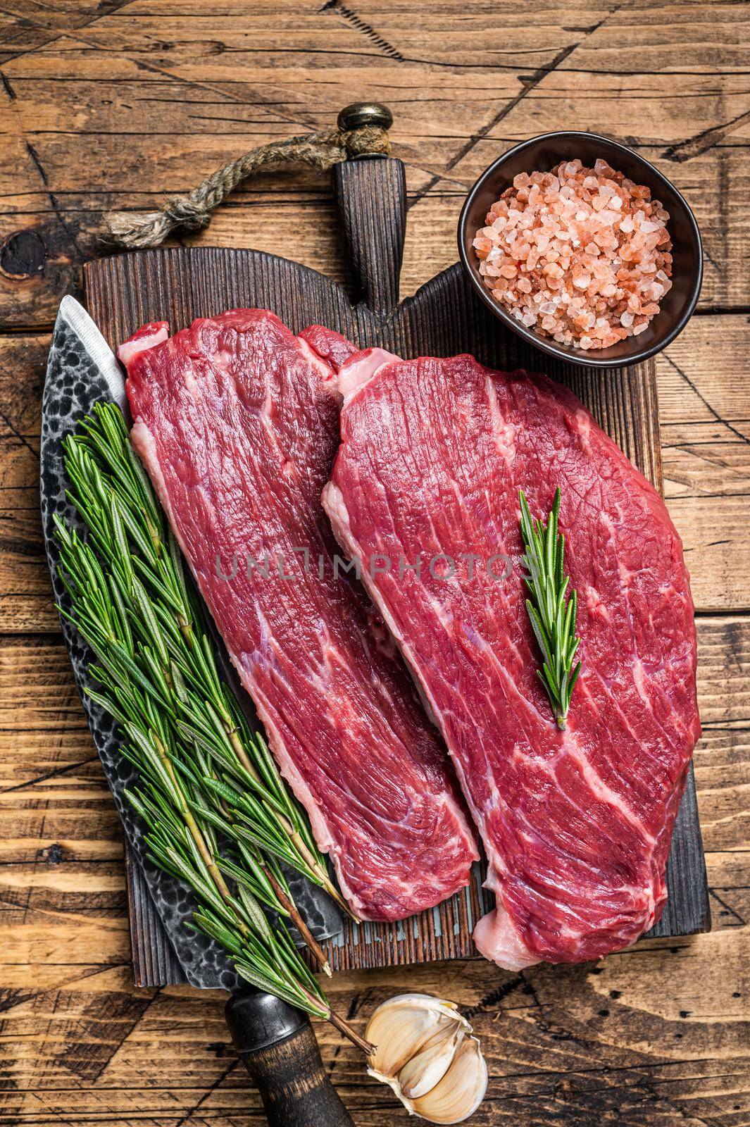 Raw rump cap steak or Picanha steak on wooden board with butcher knife. wooden background. Top view by Composter