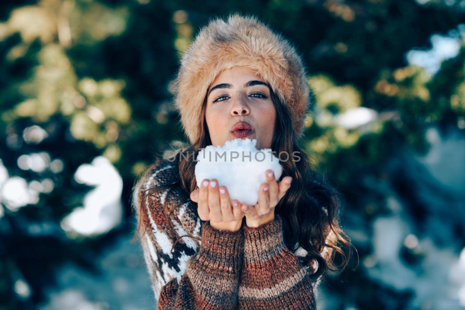 Young woman enjoying the snowy mountains in winter, in Sierra Nevada, Granada, Spain. Female wearing winter clothes playing with snow.