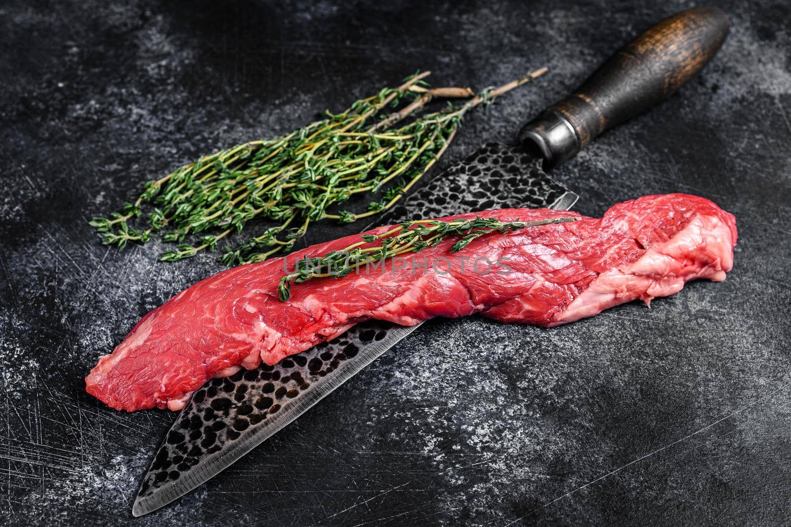 Raw skirt machete beef steak on a meat cleaver. Black background. Top view by Composter