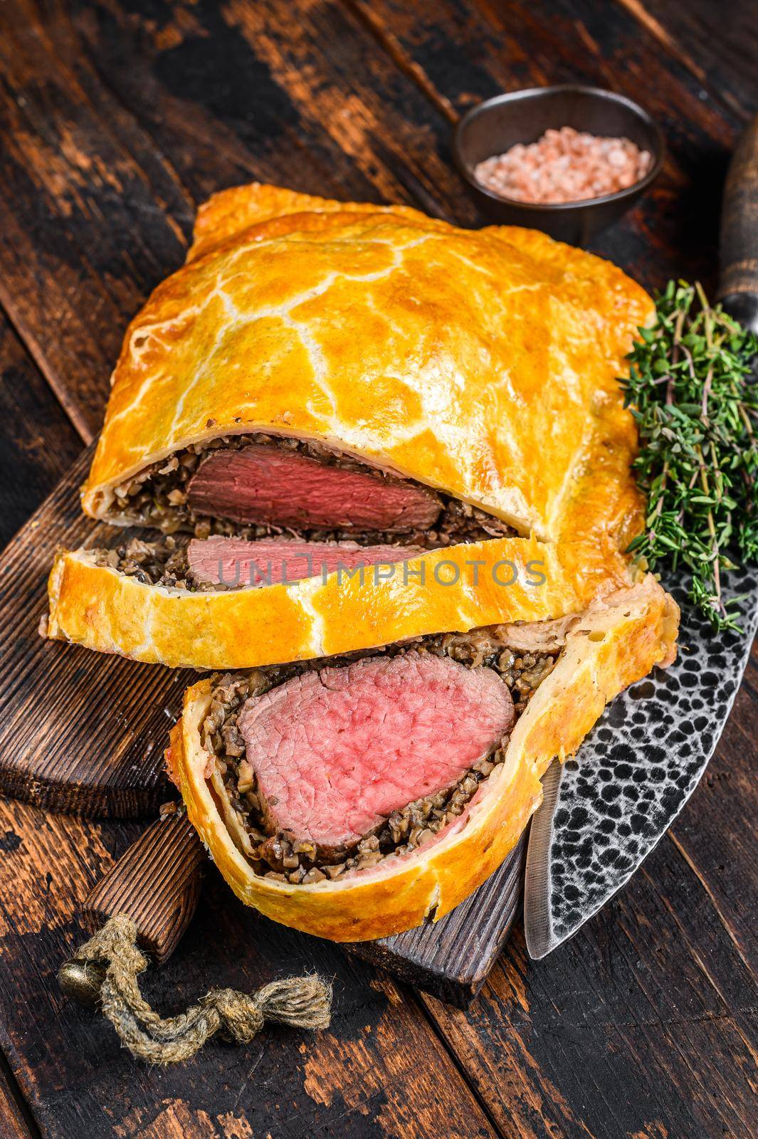 Homemade Beef Wellington puff pie with tenderloin meat on a cutting board. Dark wooden background. Top view by Composter