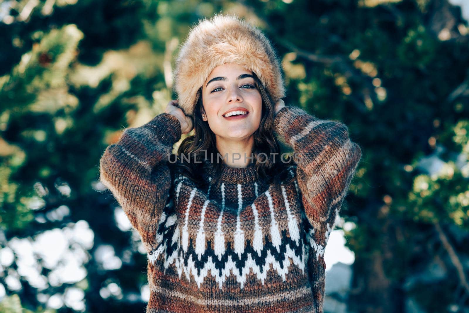 Young woman wearing fur hat enjoying the snowy mountains in winter, in Sierra Nevada, Granada, Spain. Female wearing winter clothes.