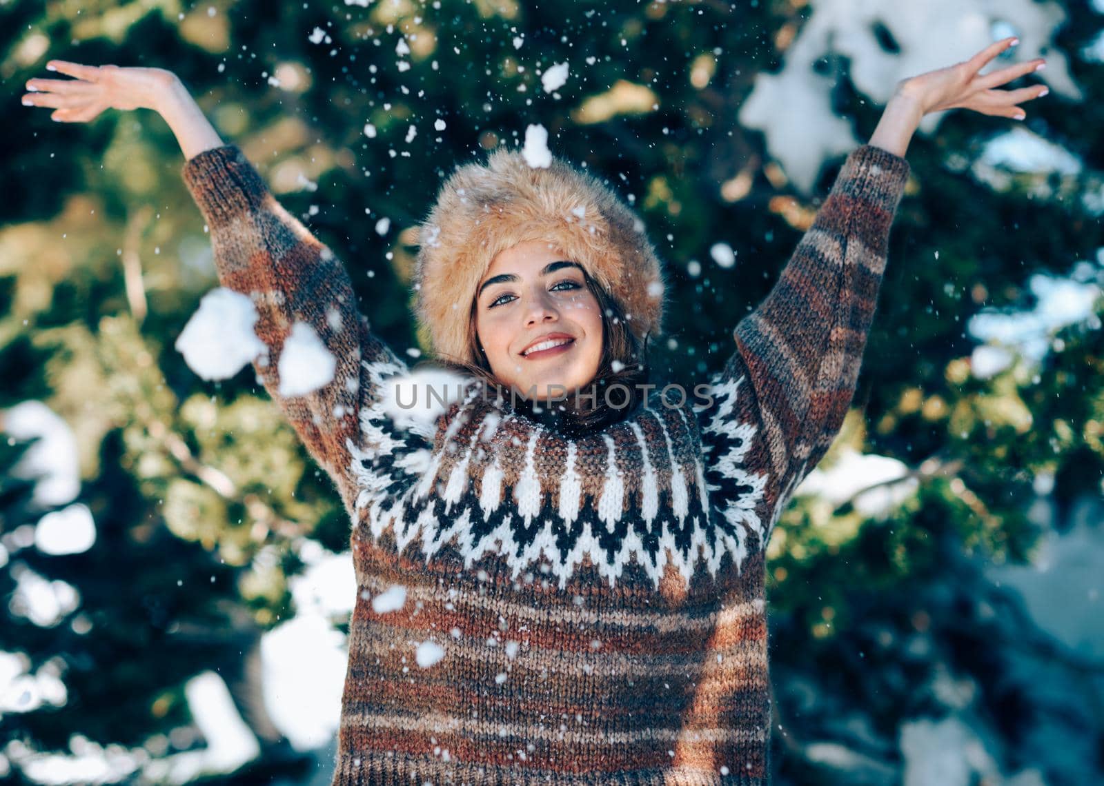Young woman enjoying the snowy mountains in winter, in Sierra Nevada, Granada, Spain. Female wearing winter clothes playing with snow.