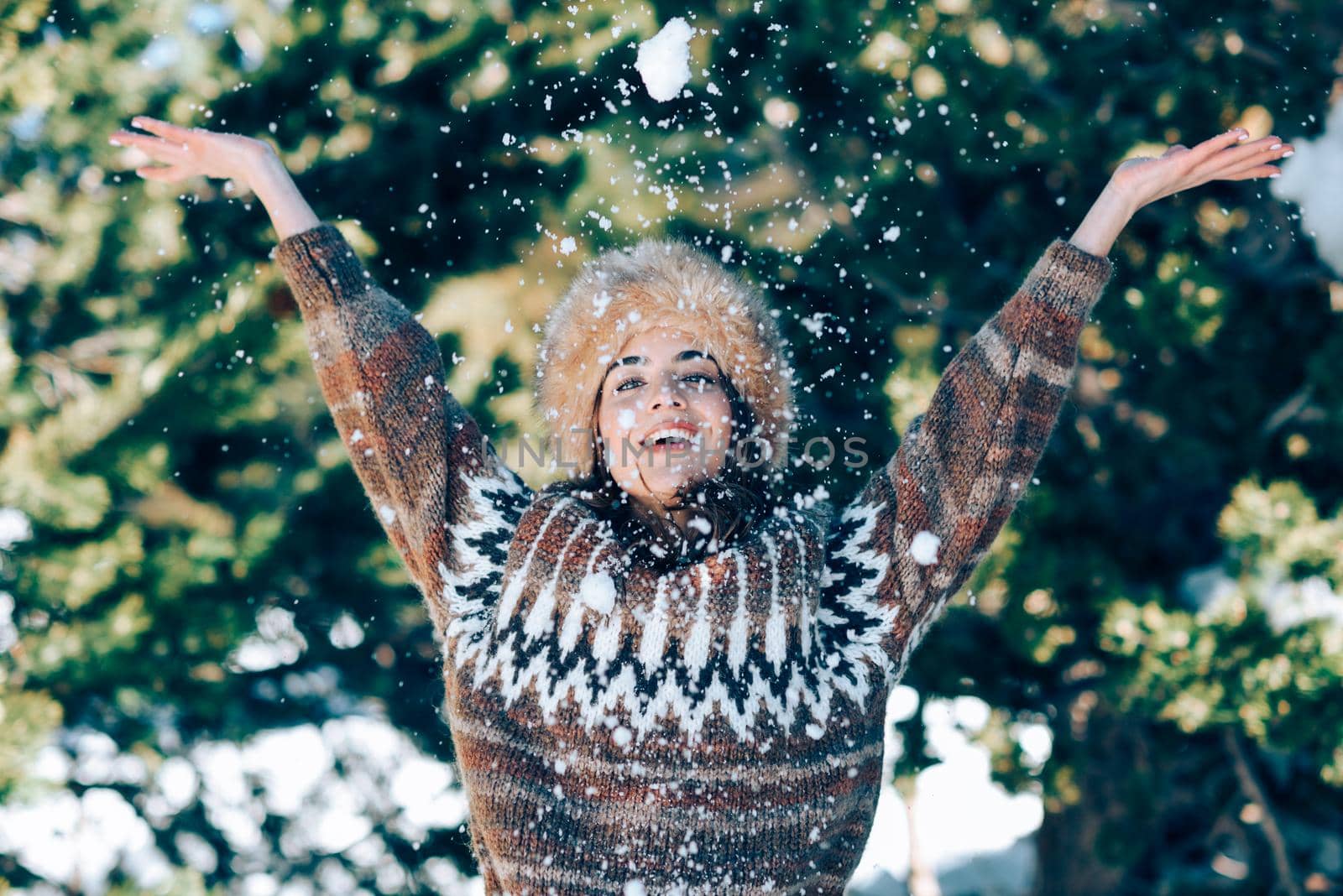 Young woman enjoying the snowy mountains in winter, in Sierra Nevada, Granada, Spain. Female wearing winter clothes playing with snow.