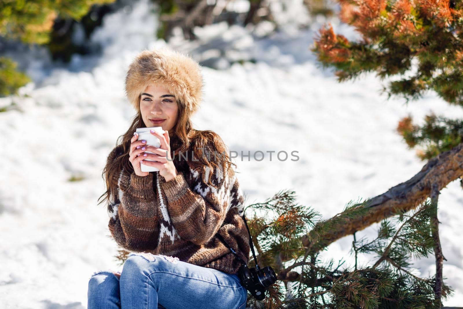 Female wearing winter clothes drinking hot coffee. Young woman enjoying the snowy mountains in winter, in Sierra Nevada, Granada, Spain.