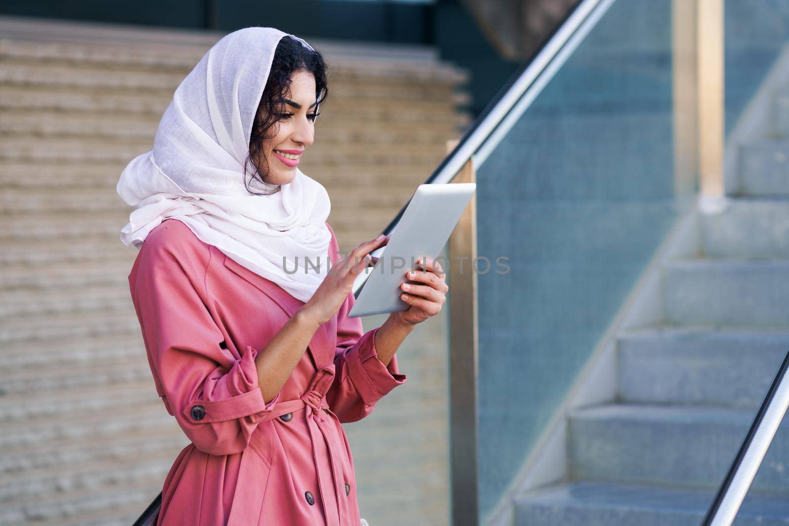 Young Arab woman wearing hijab headscarf using digital tablet in business environment.