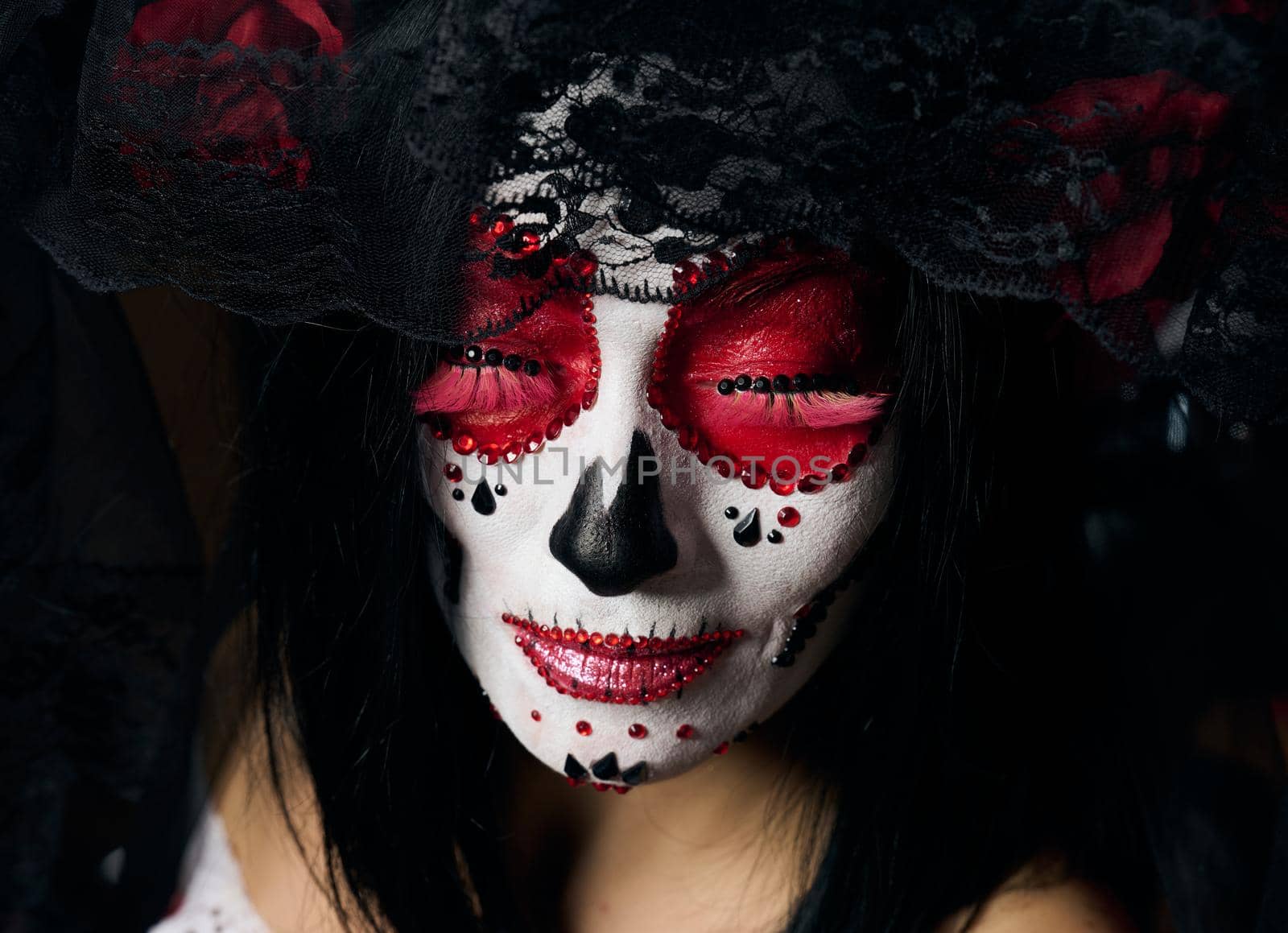 portrait of a beautiful woman with closed eyes and a sugar skull makeup with a wreath of flowers on her head, close up