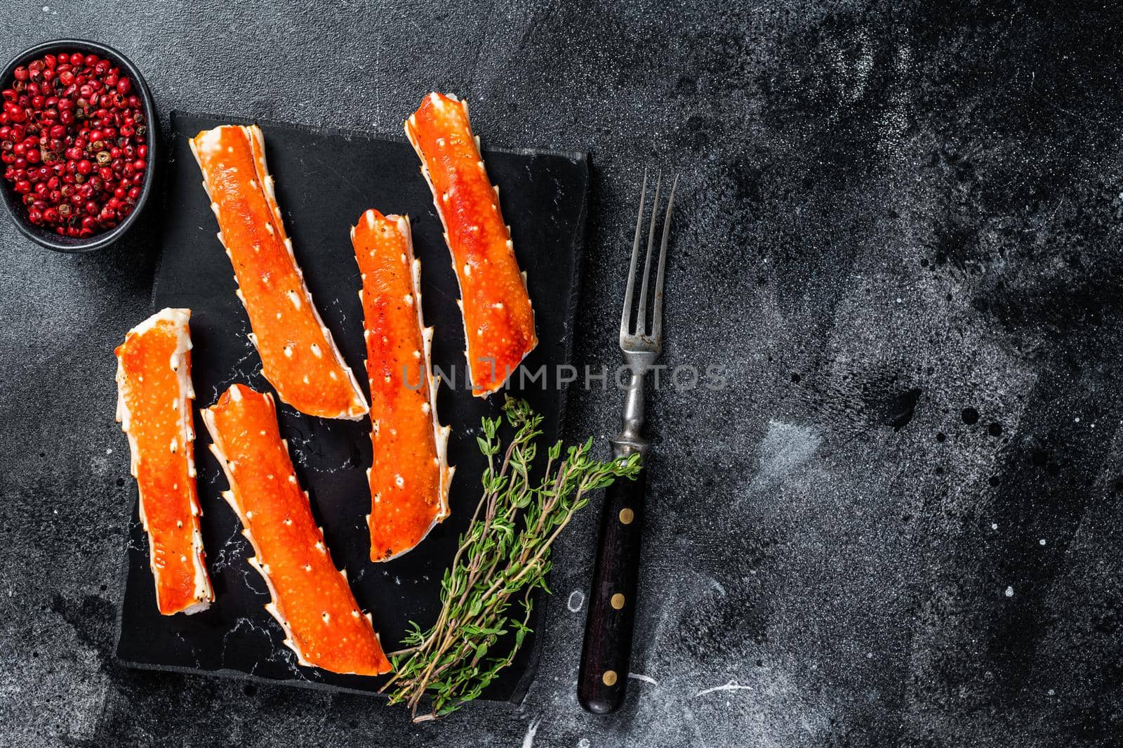 Crab legs Phalanx on a marble board with thyme. Black background. Top view. Copy space by Composter