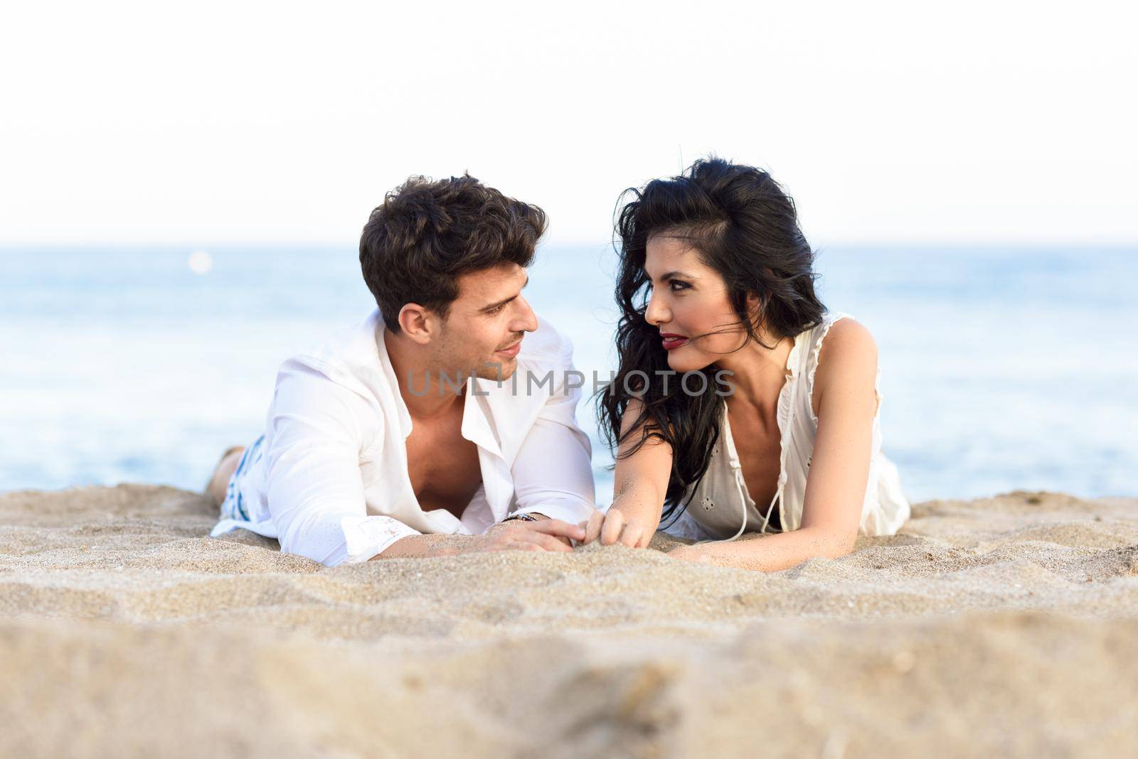 Young happy couple lying on the sand in a beautiful beach by javiindy