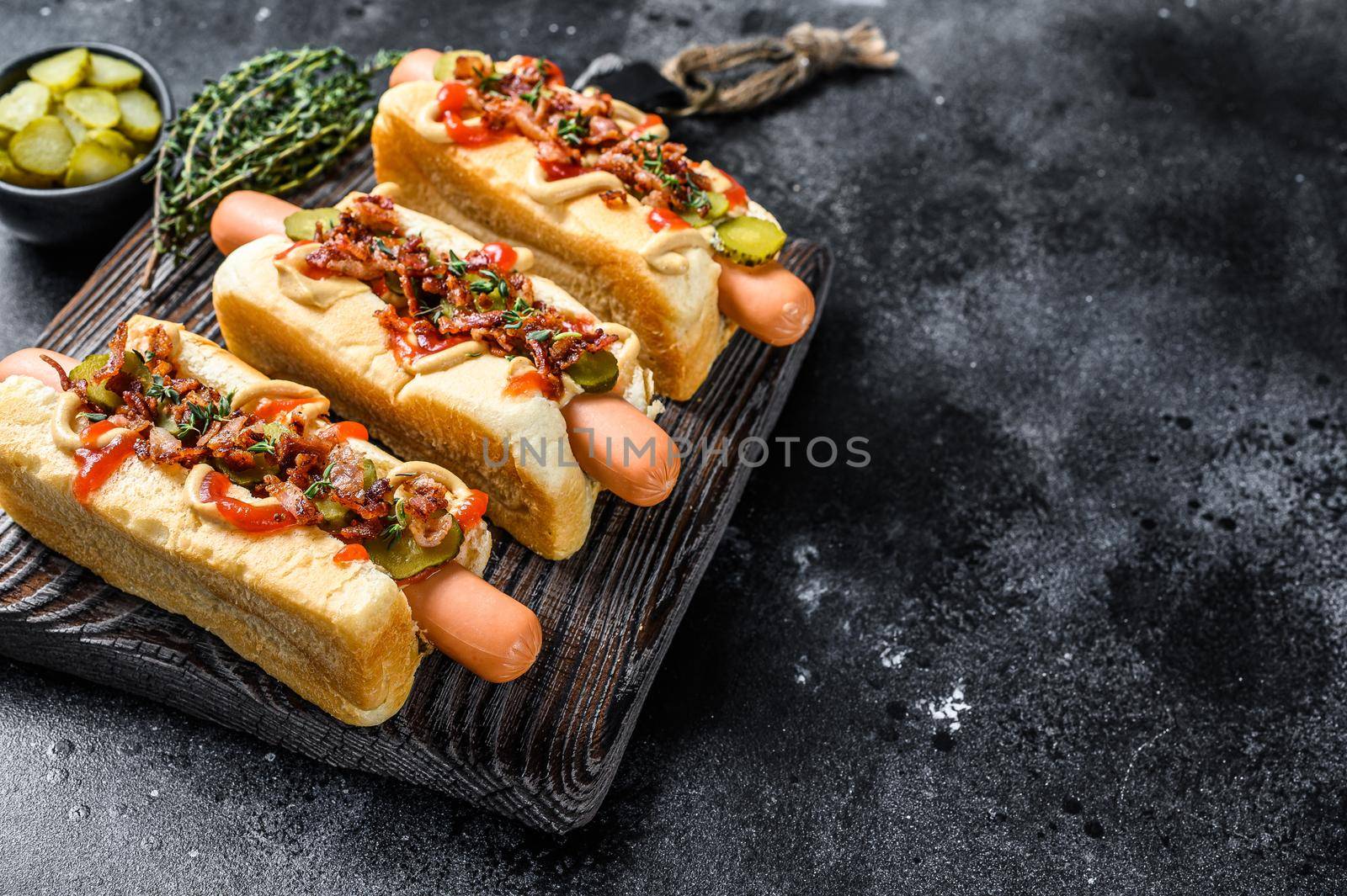 Hot dogs with different toppings. Dark wooden background. Top view. Copy space.