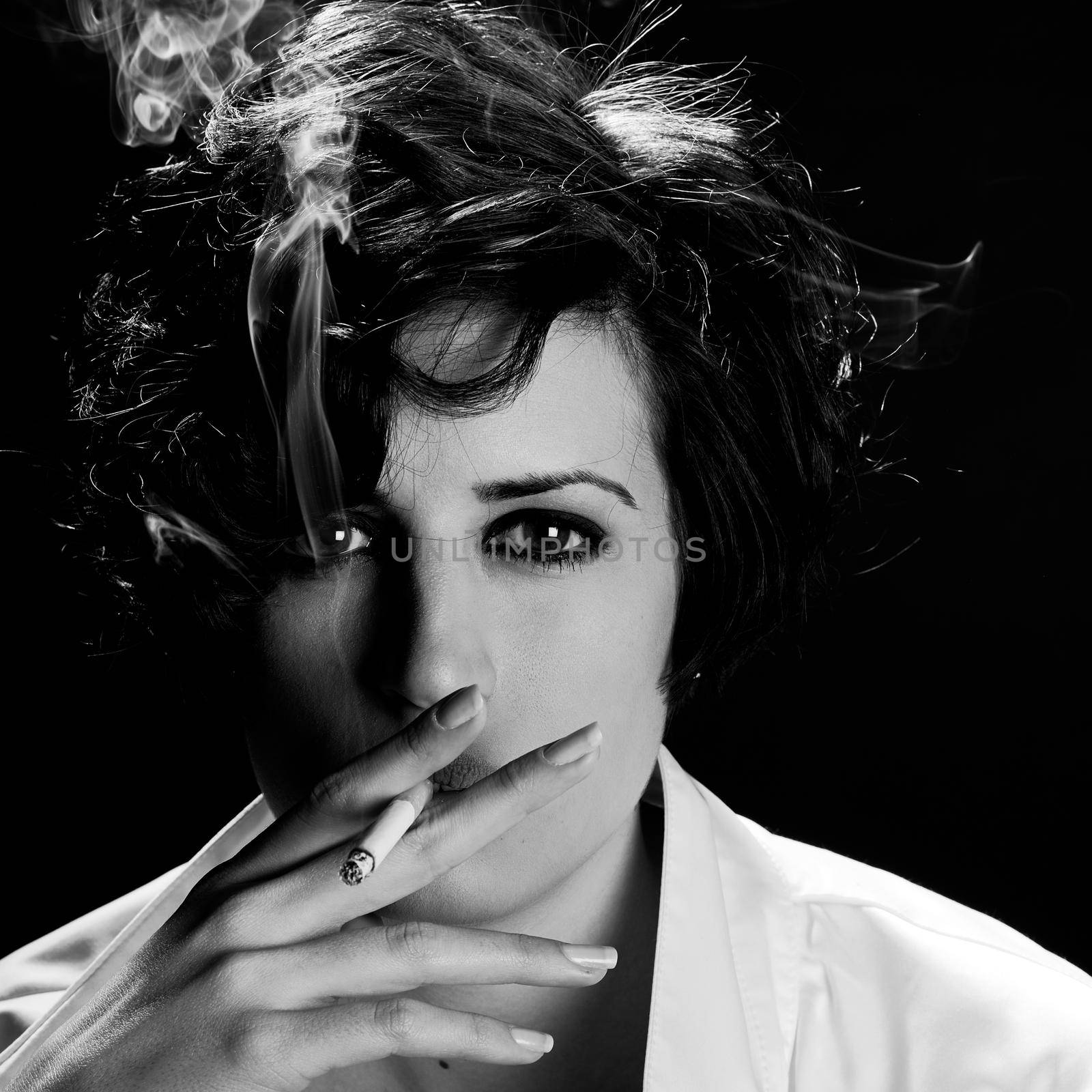 Elegant brunette woman smoking a cigarette on black background by javiindy