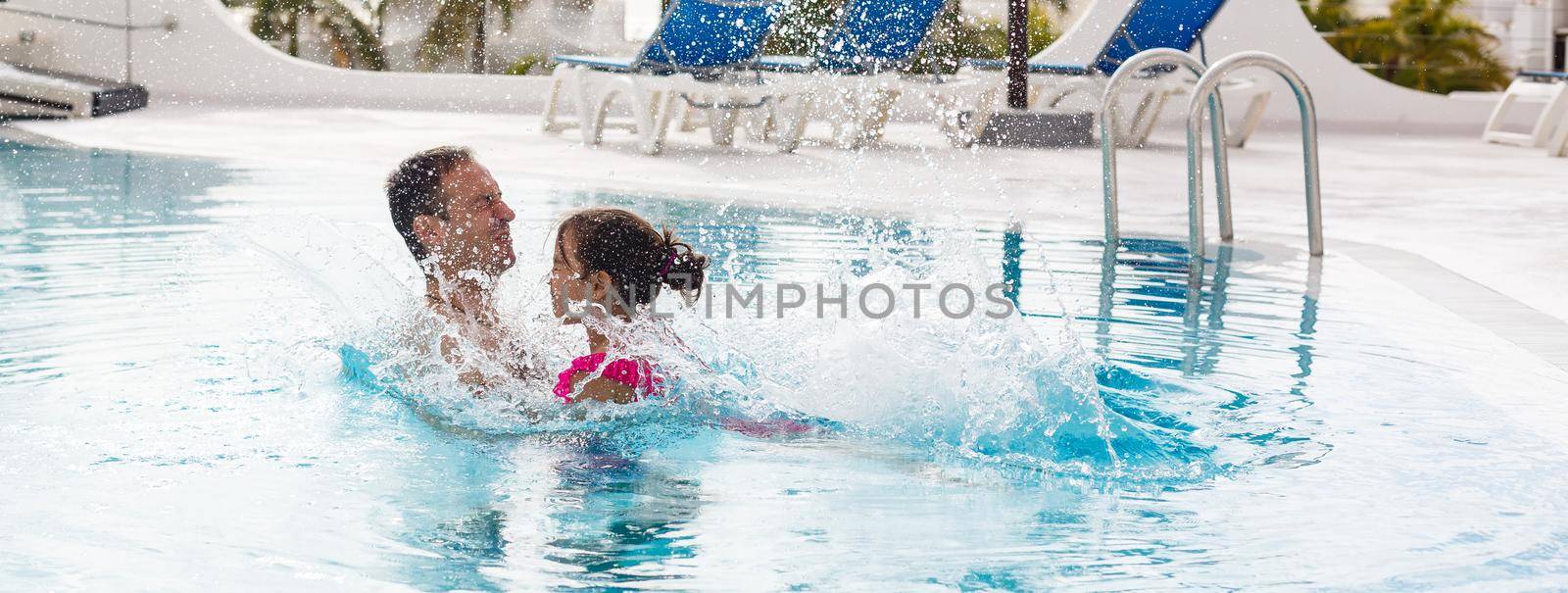 Father playing with his daughter in swimming pool.