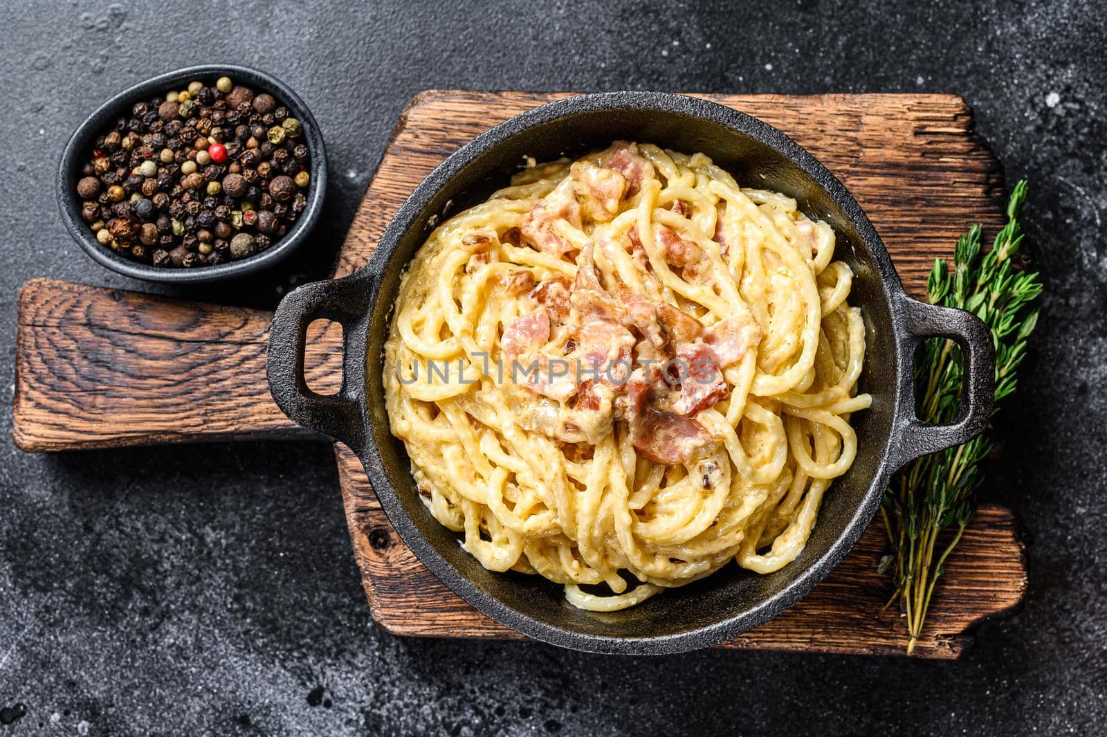 Pasta Carbonara with bacon and parmesan in a pan. Black background. top view by Composter