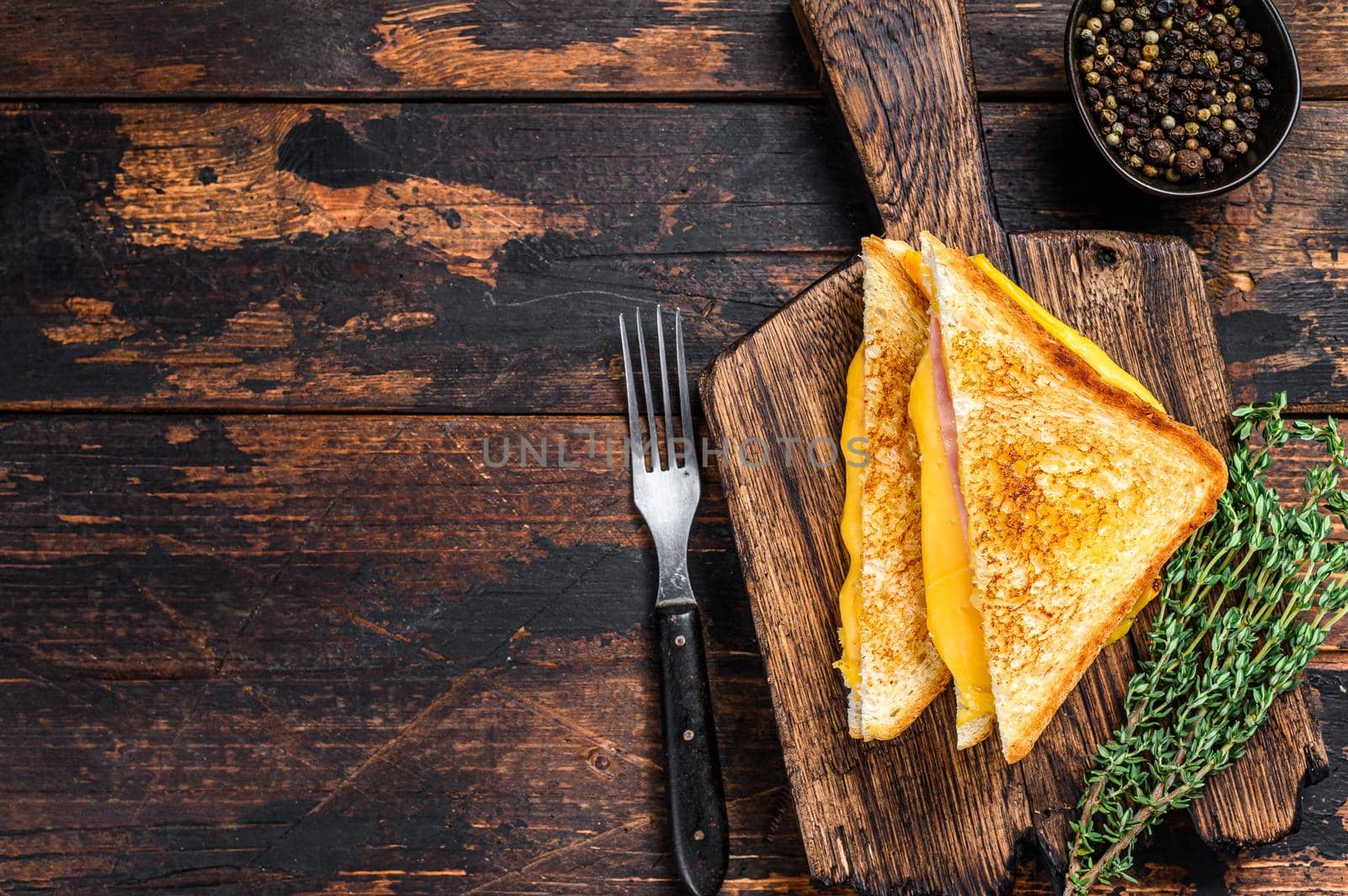 Fried ham and melted cheese sandwich. Dark wooden background. Top view. Copy space.