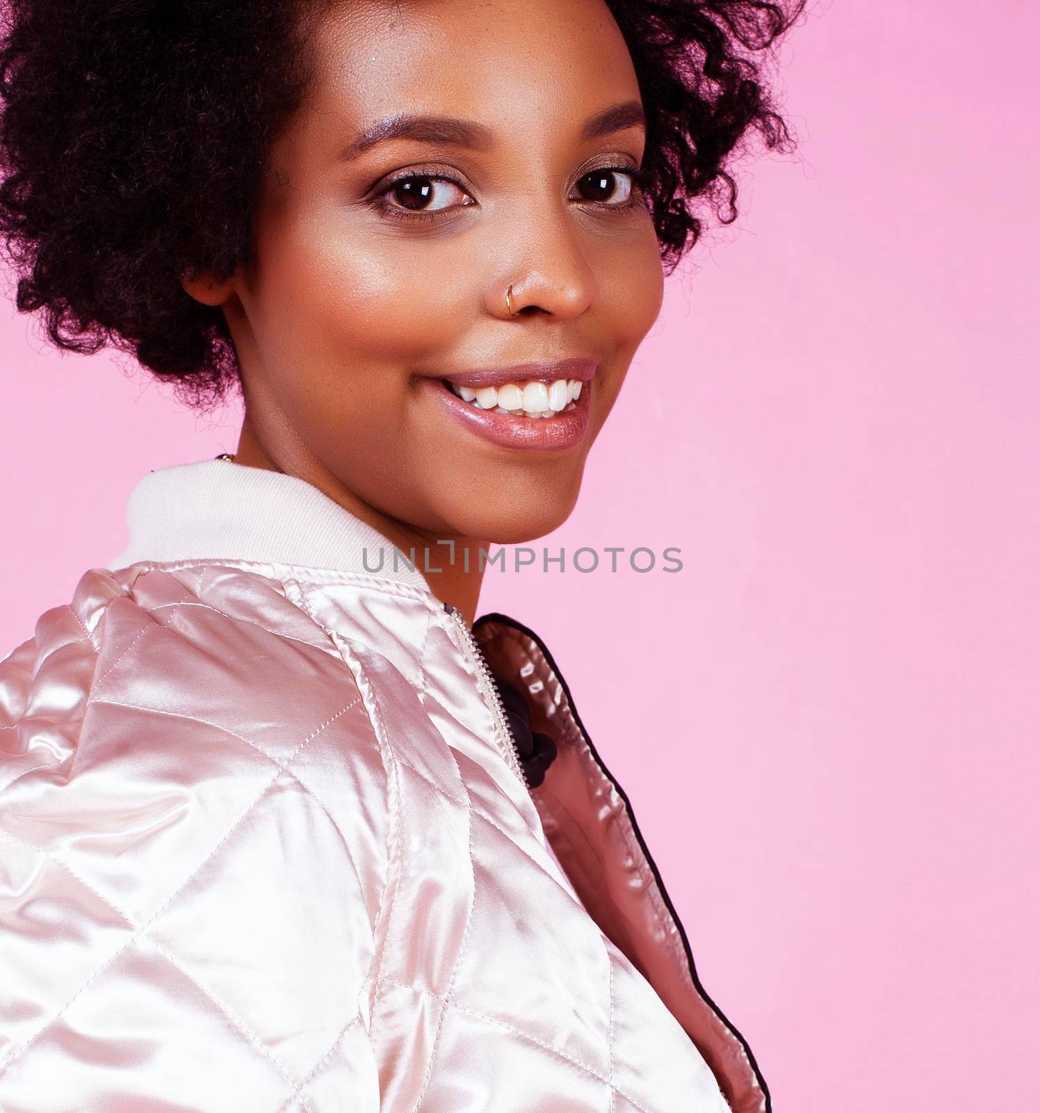 young pretty fashion styled african girl posing emotional cheerful on pink background, lifestyle people concept close up
