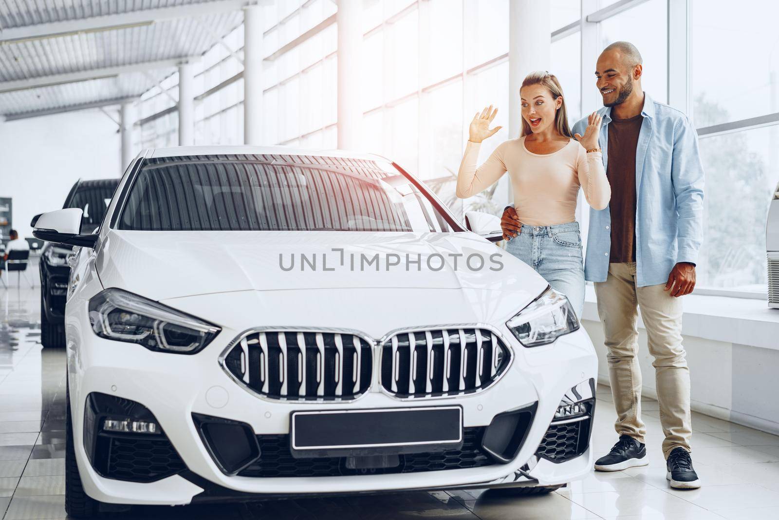 Young happy couple choosing a car in car dealership by Fabrikasimf