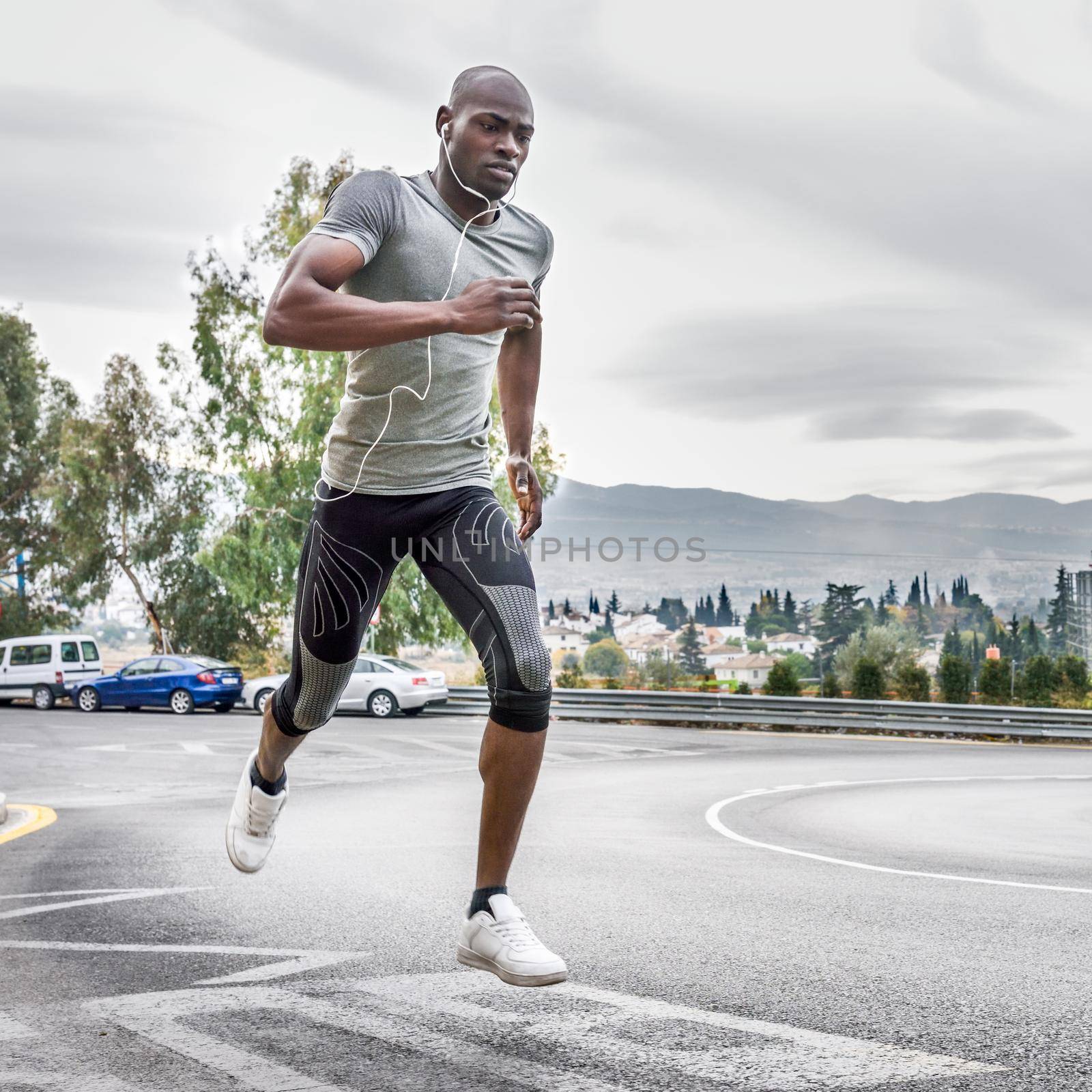 Black man running outdoors in urban road. by javiindy