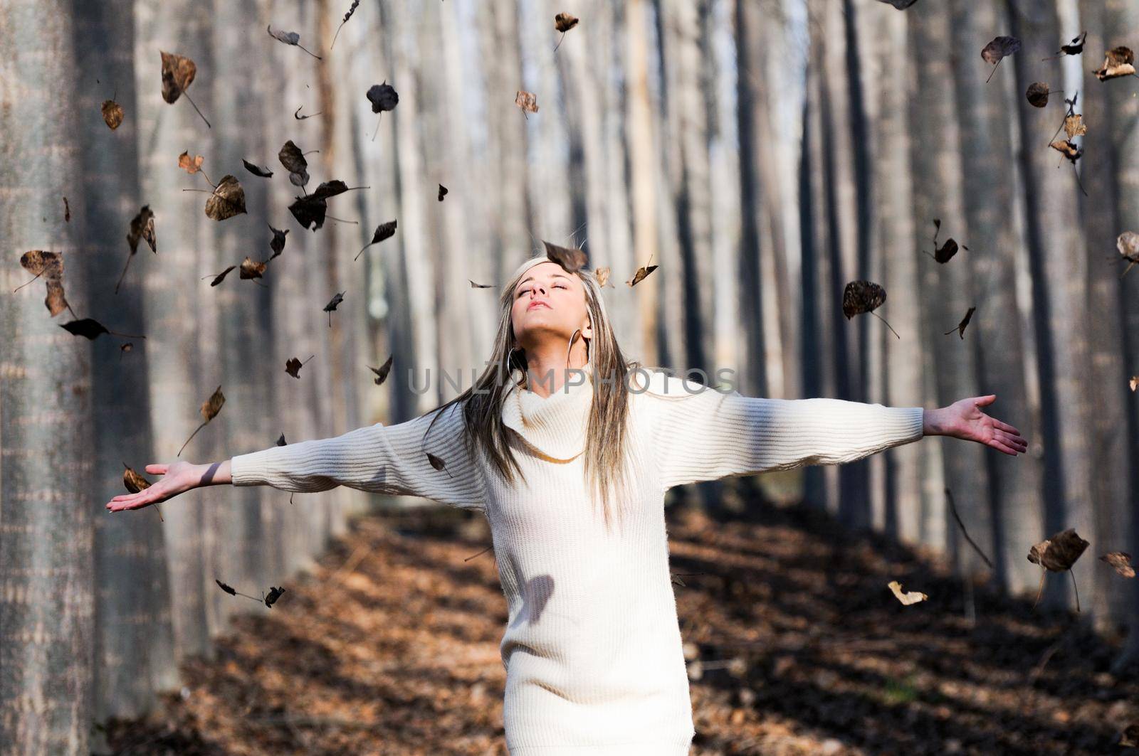 Beautiful blonde girl with falling leaves in the autumn park