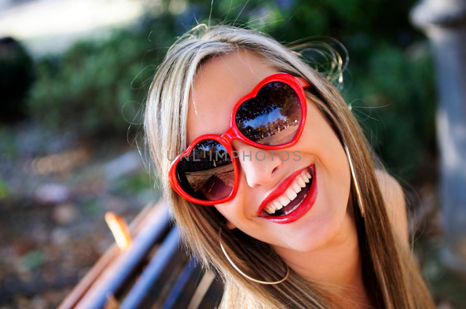 Funny girl with red heart glasses in a park